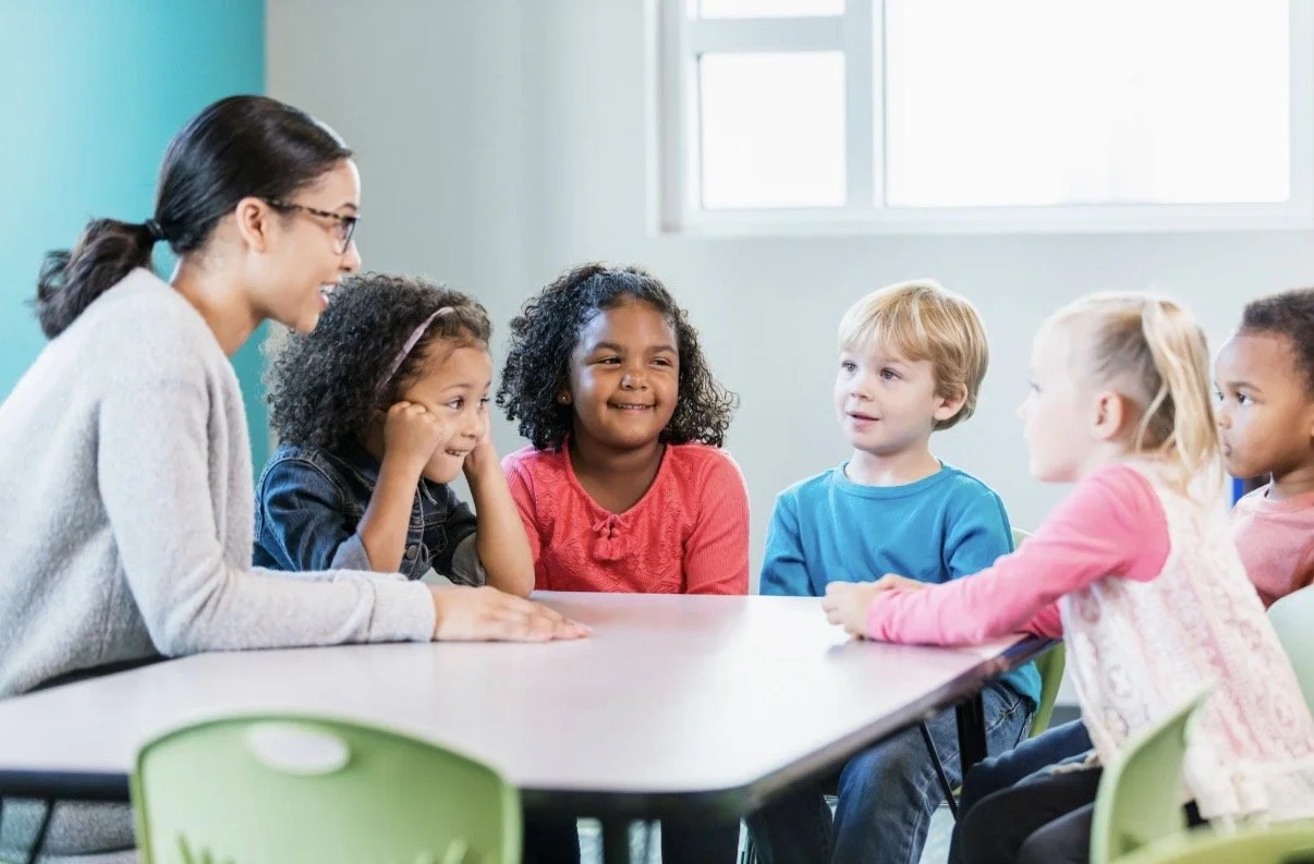 Daycare teacher supporting young children in a classroom with positive behavior strategies and individualized learning support.