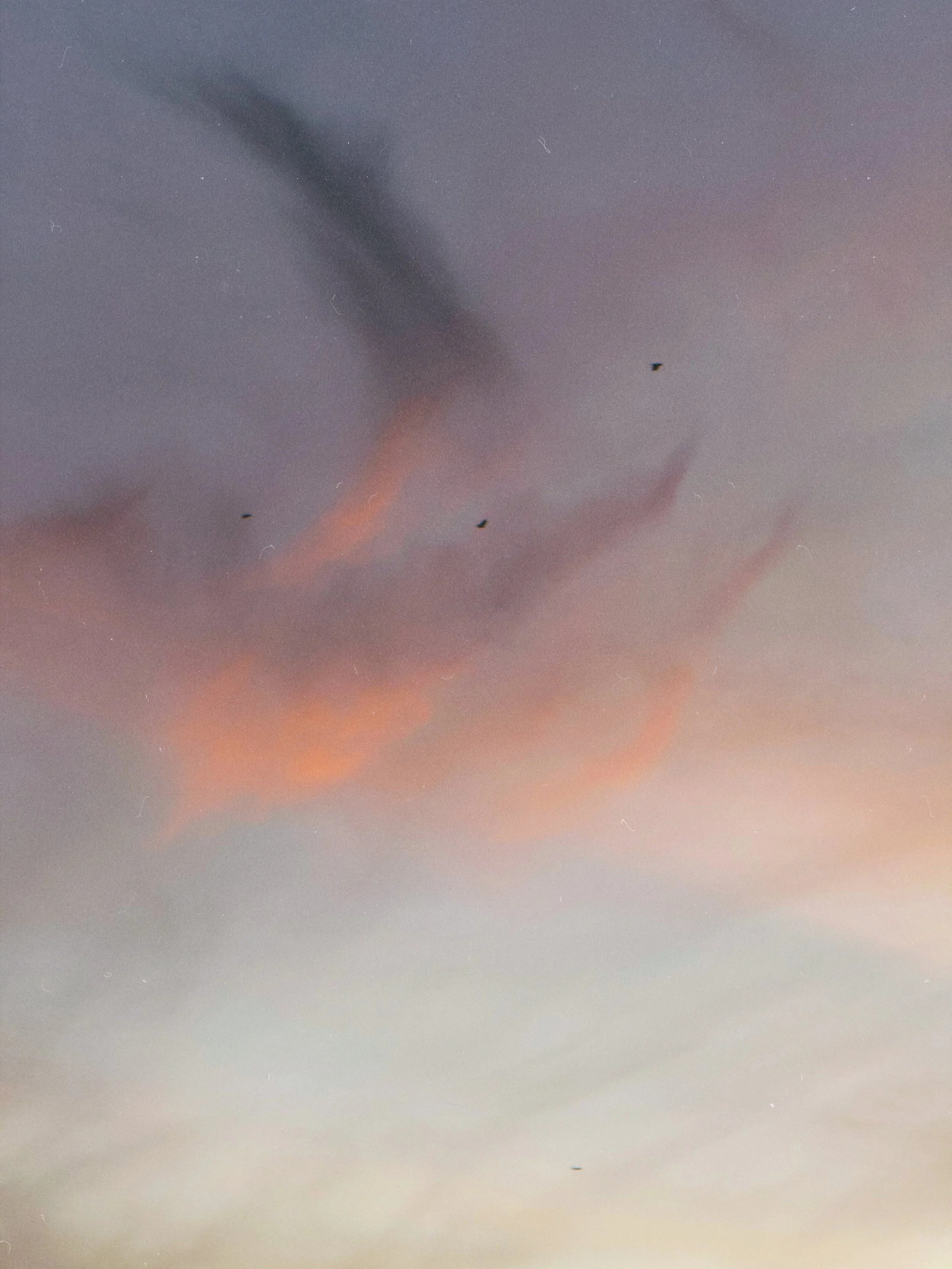 A colorful sky at dusk with pink and orange clouds and some faint stars visible.