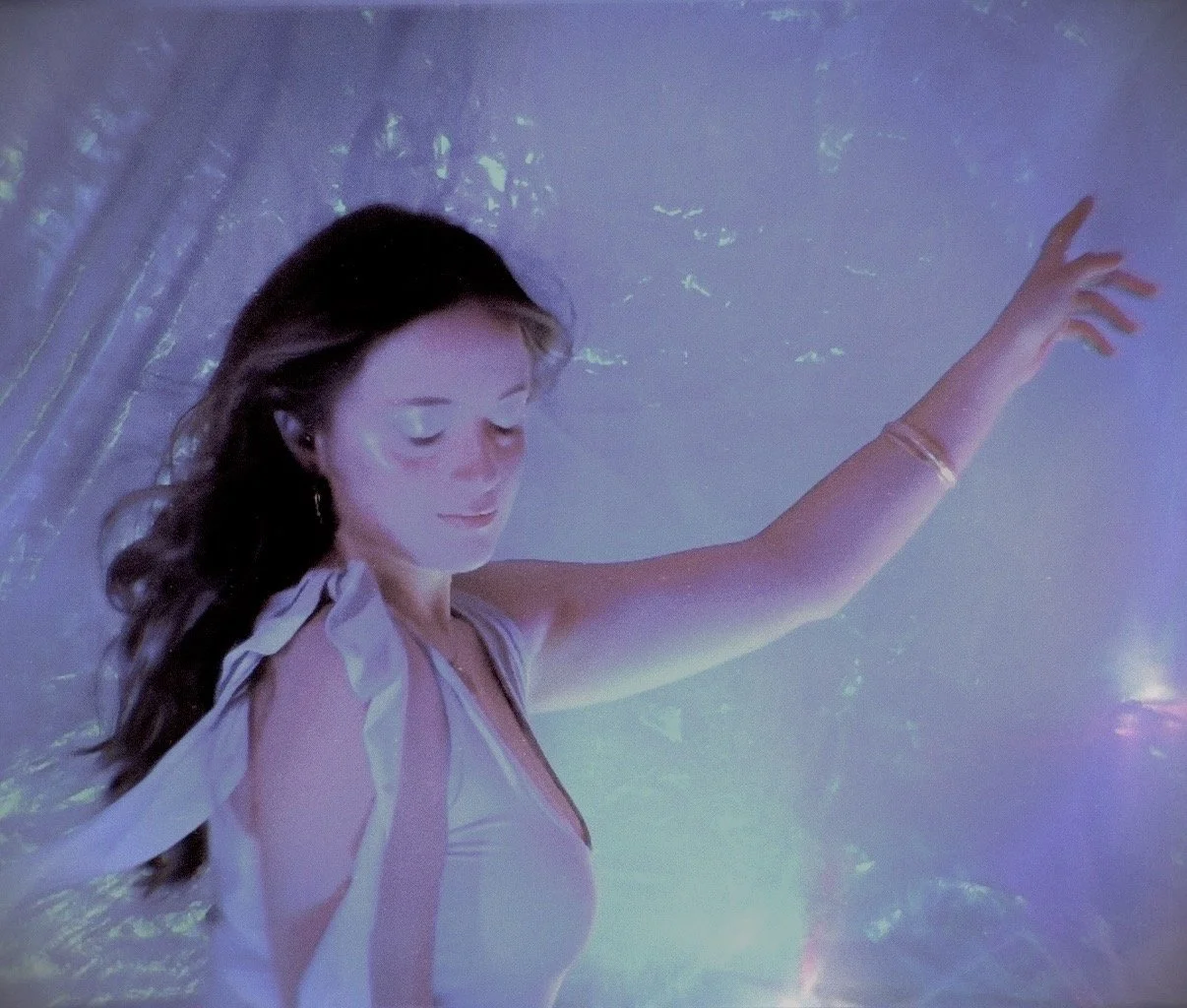Natalia James raising her arm in soft purple and blue projected light.