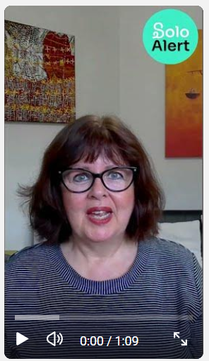 A woman with curly brown hair and glasses speaking, with colorful artwork on the wall behind her and a "Solo Alert" badge in the top right corner.