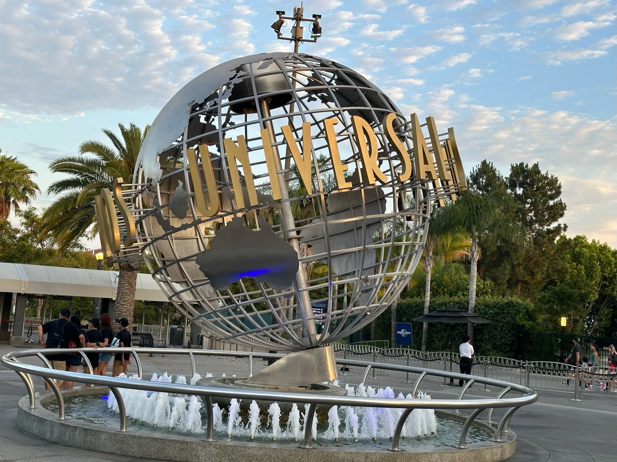 The Epcot globe at Disney World with people walking around and trees in the background during the day.