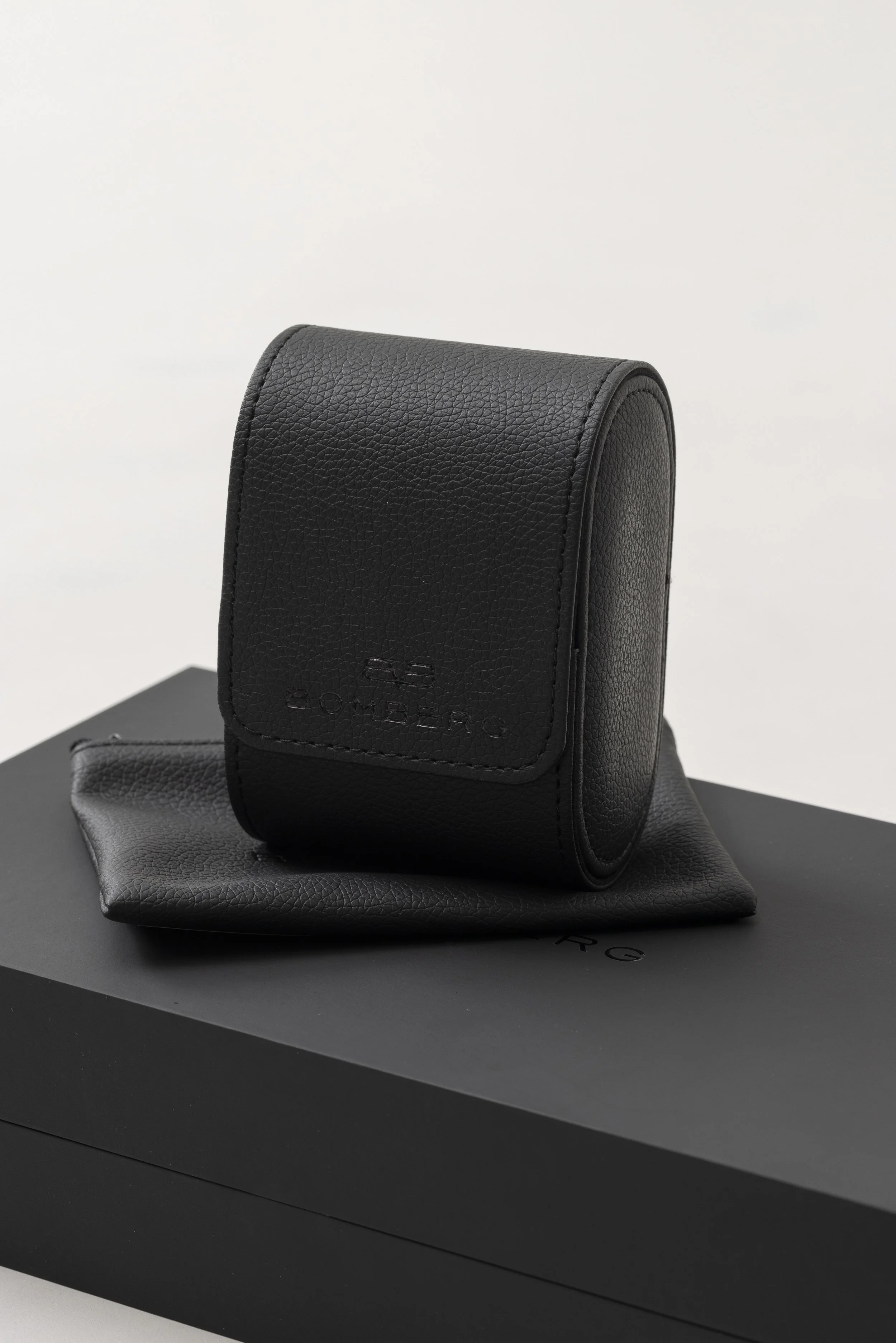 Black textured leather handbag on top of a black designer box.