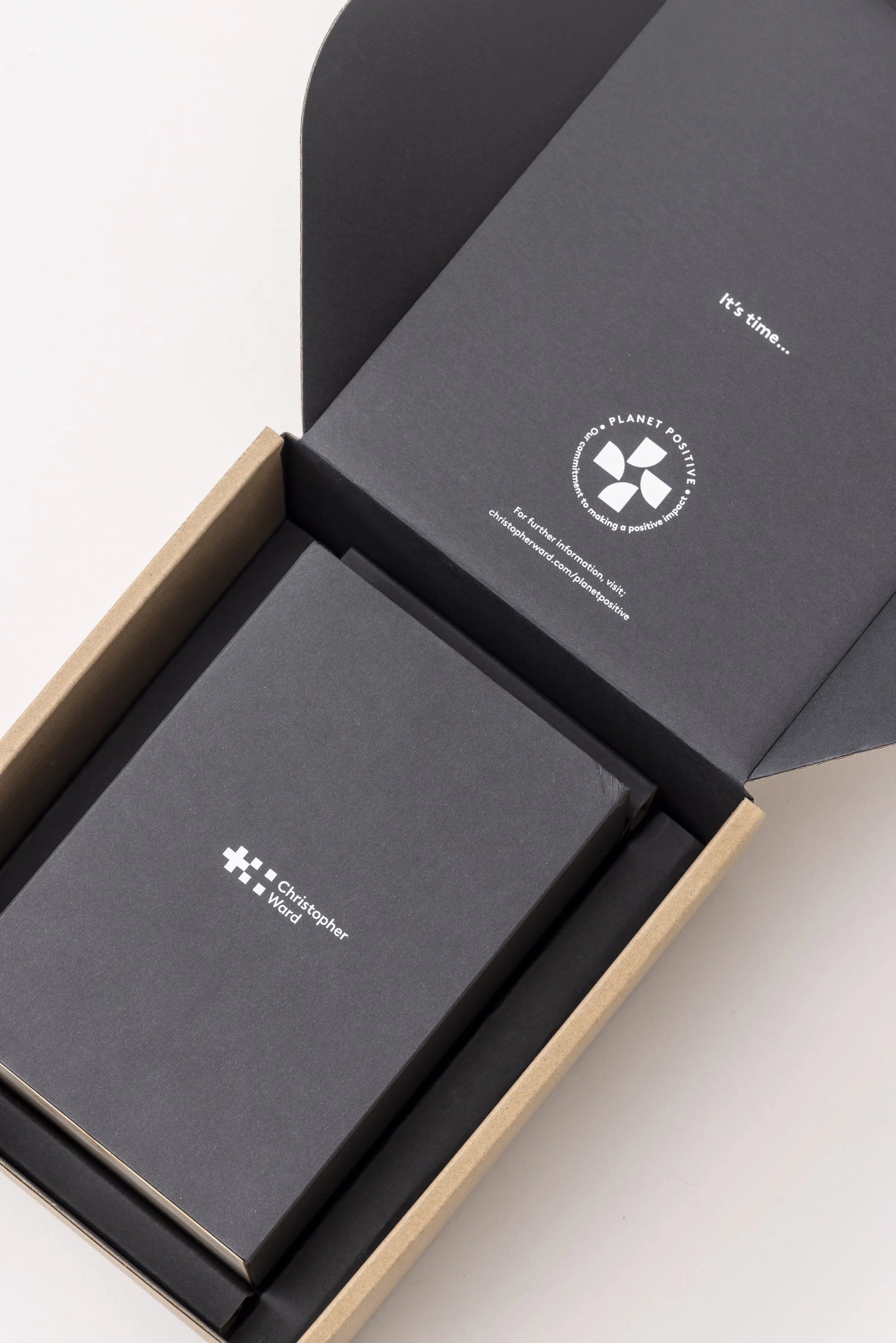 Close-up of black boxes inside a cardboard box, with white printed logos and text, part of a packaging or product box set.
