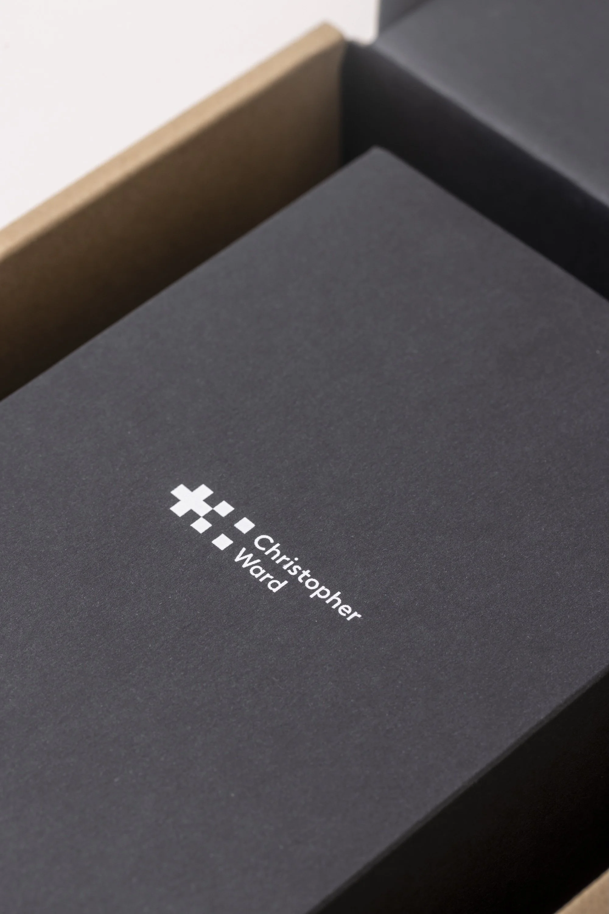 Close-up of a black box with white text displaying a name, 'Christopher Ward,' and a series of pixelated white icons.