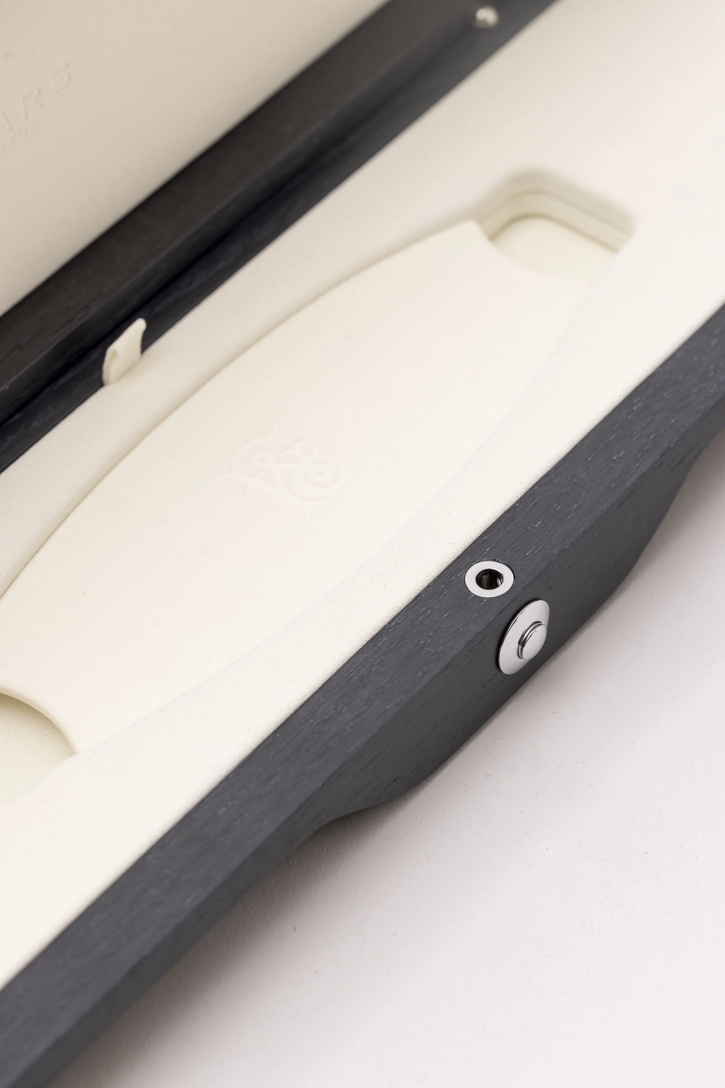 Close-up of a white and gray electronic device with buttons and a slot, possibly a vape or electronic cigarette, on a white surface.