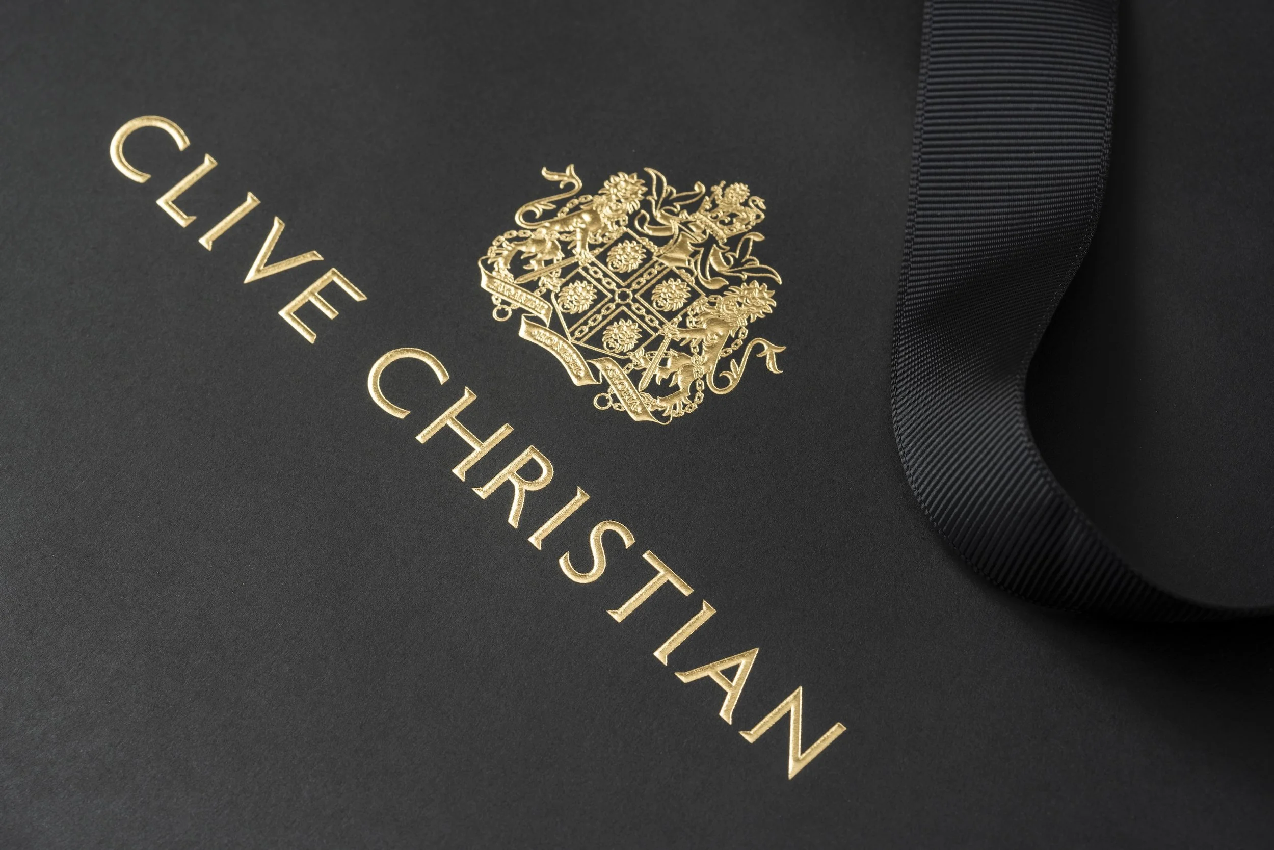 Close-up of a luxury chocolate box with gold embossed text and emblem, including a lion and floral design on black textured background.