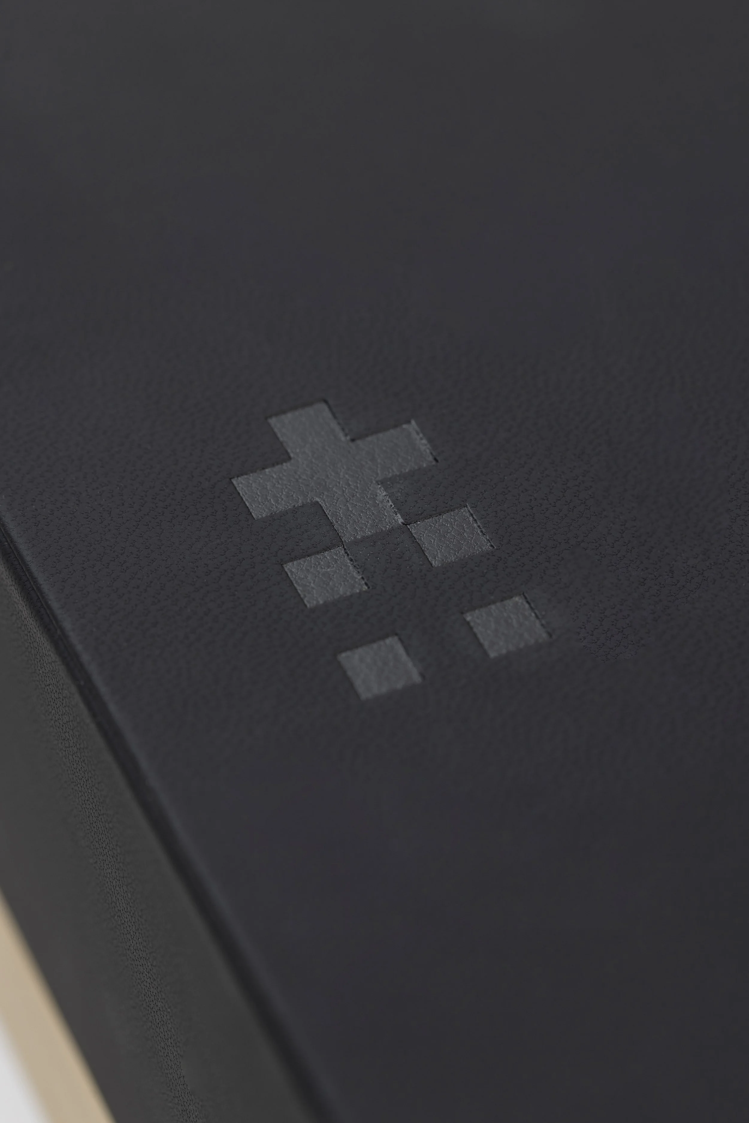 Close-up of a black electronic device with a silver cross-shaped button.