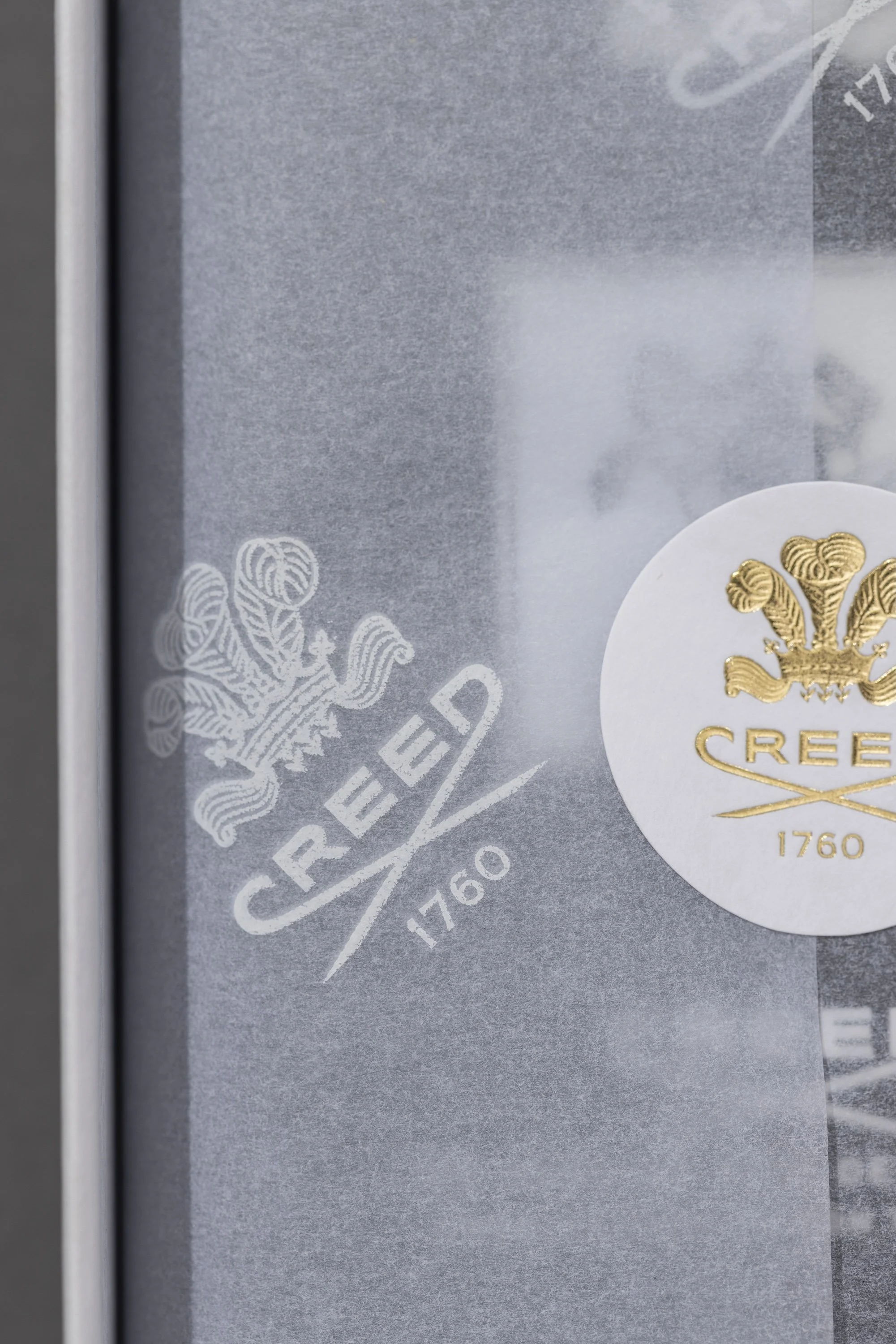 Close-up of a label on a silver and gold-colored box, displaying a detailed crest with a crown and decorative elements, along with the text '1760' and partial text 'CRE' visible.