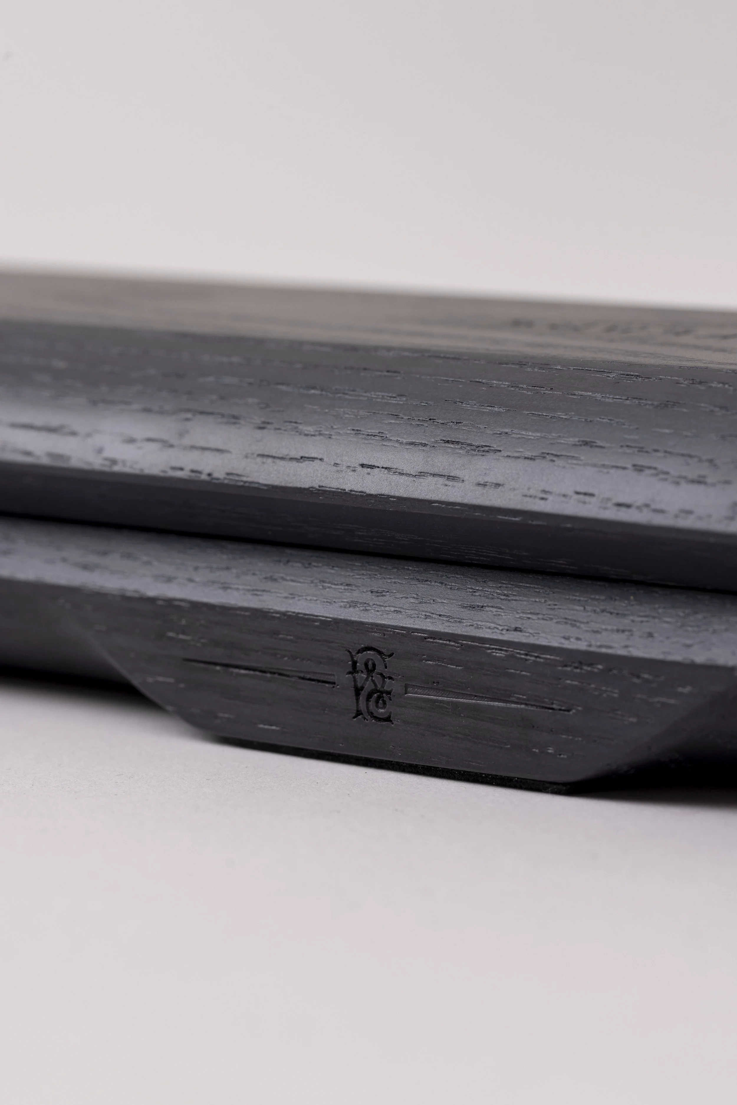Close-up of a book with a black cover, showing a small part of an illustration or logo on the spine, resting on a white surface.