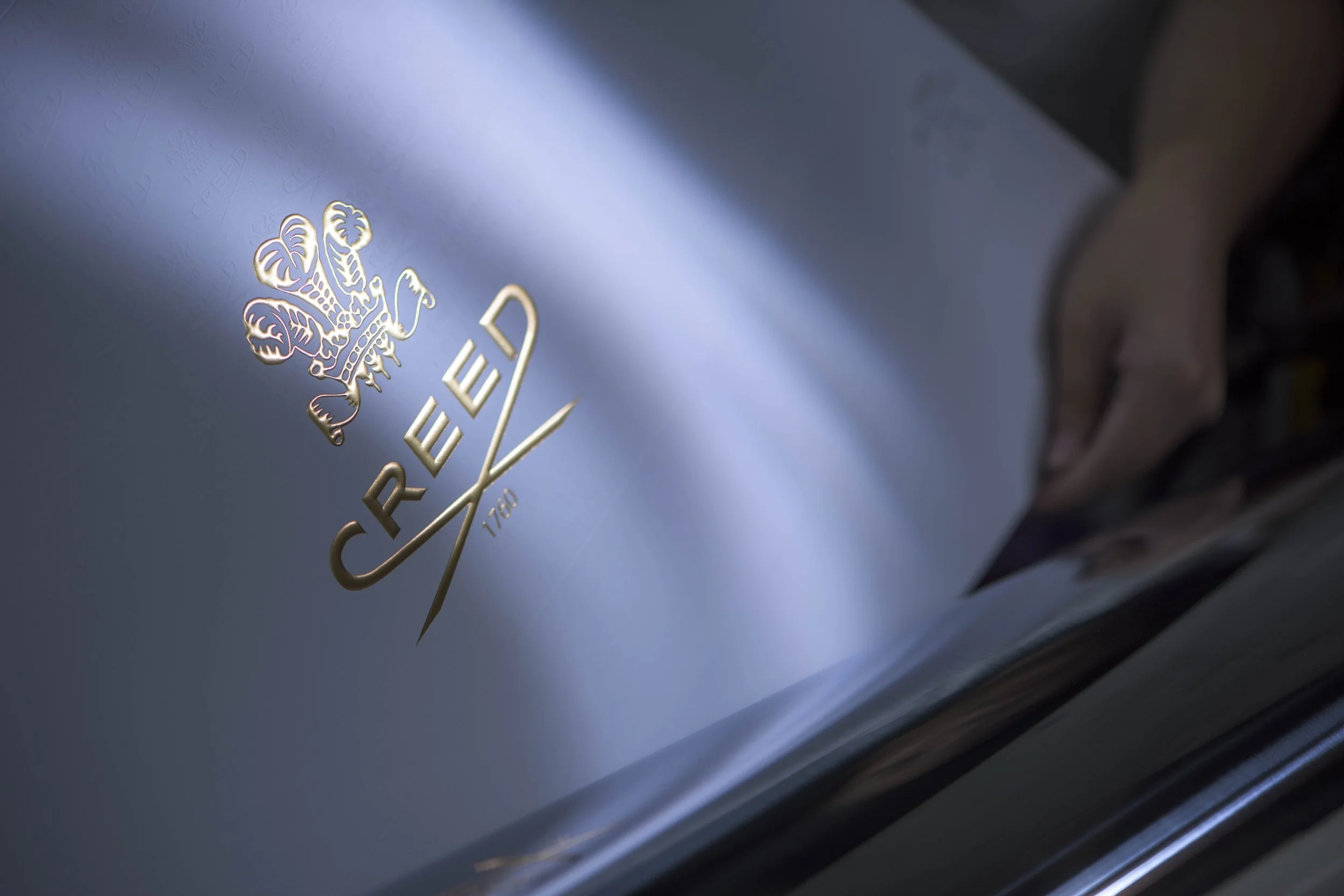 Close-up of a metallic emblem with leaves and the word 'CREDENT' on a reflective surface.