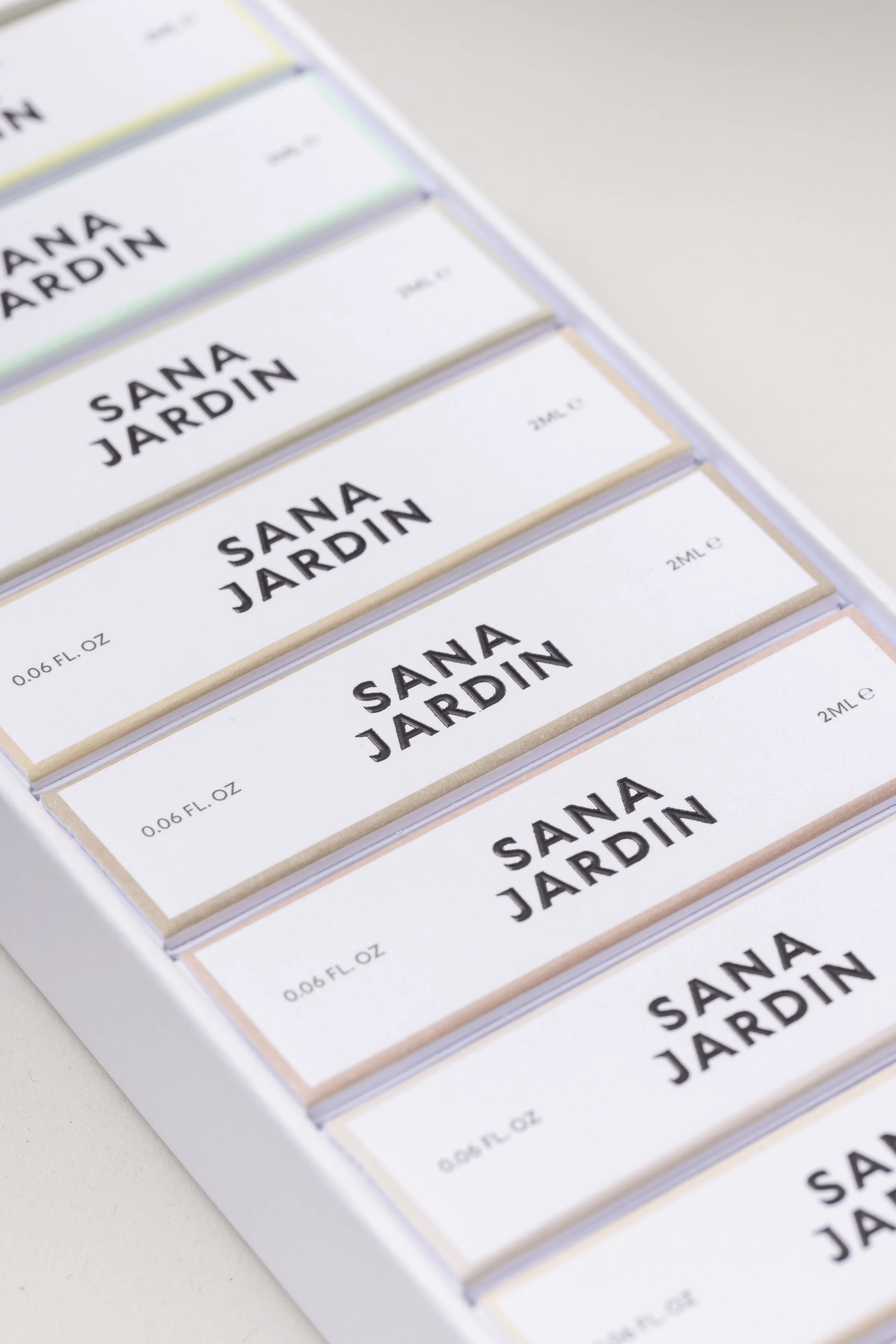 Close-up photo of several individual perfume or cosmetic boxes with the brand name 'SANA JARDIN' printed on them, arranged in a neat row.