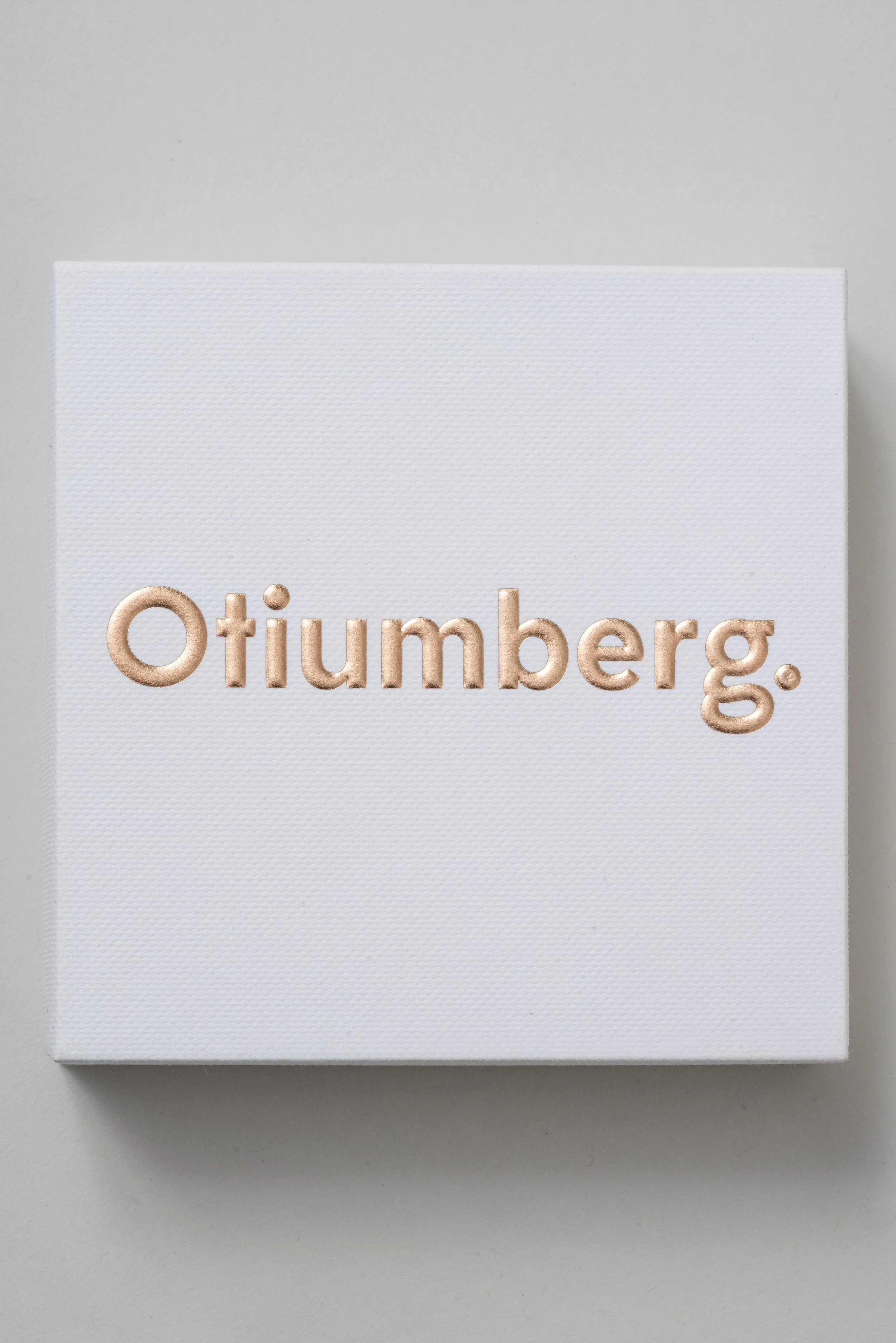 Close-up of a white box with the word 'Otibers.' written in rose gold embossed letters.