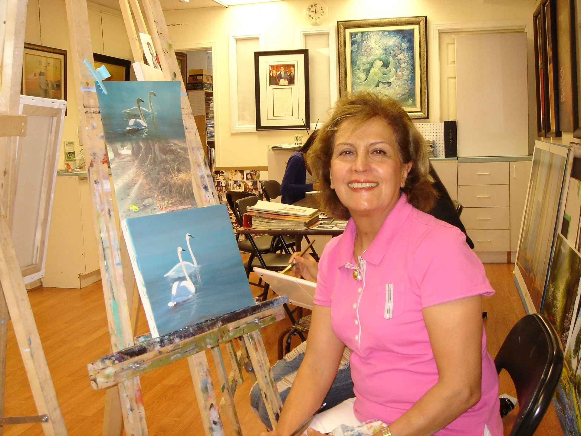 Artist seated beside her easel in the studio