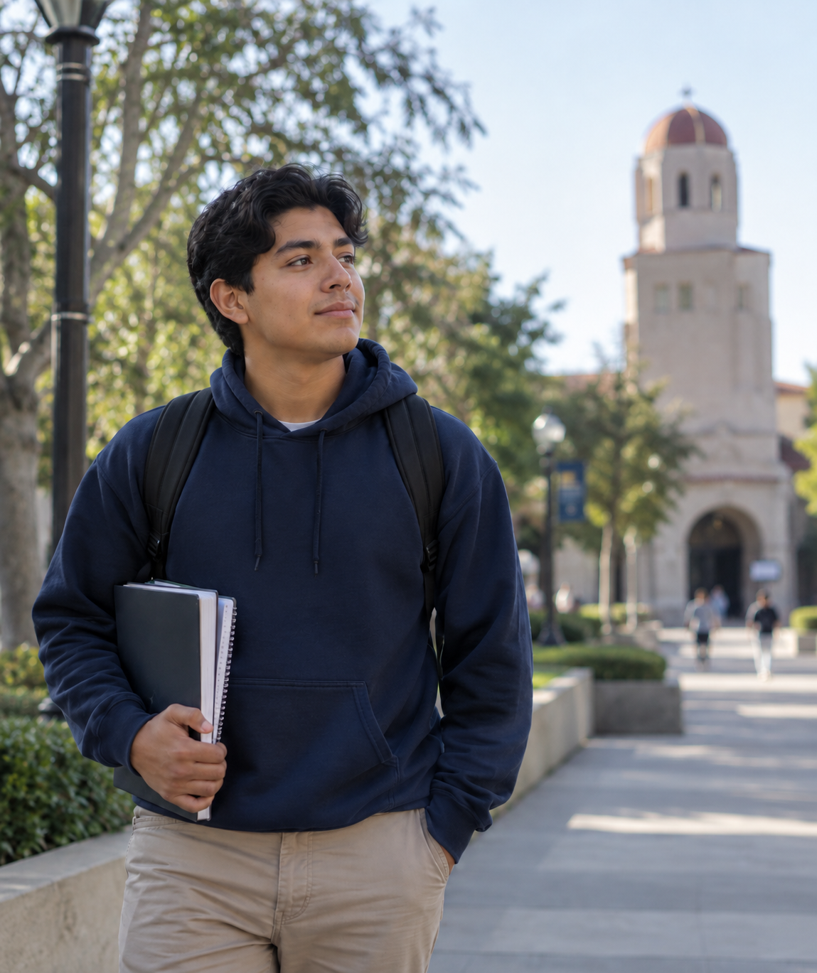 Student walking on a college campus with notebooks.