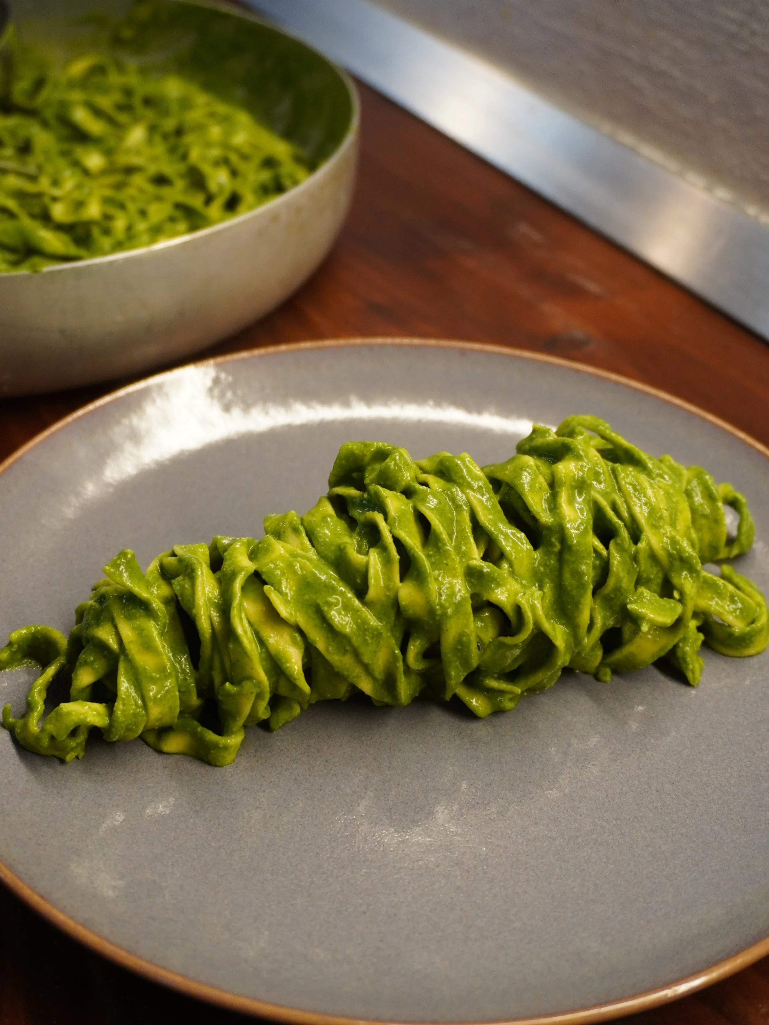 Pasta verde ripiena o formata a nidi su un piatto grigio