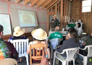 Attendees seated in a timber-framed room listening to a presenter at an Earth Month talk