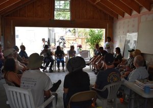 Workshop audience seated in an open-sided wooden pavilion