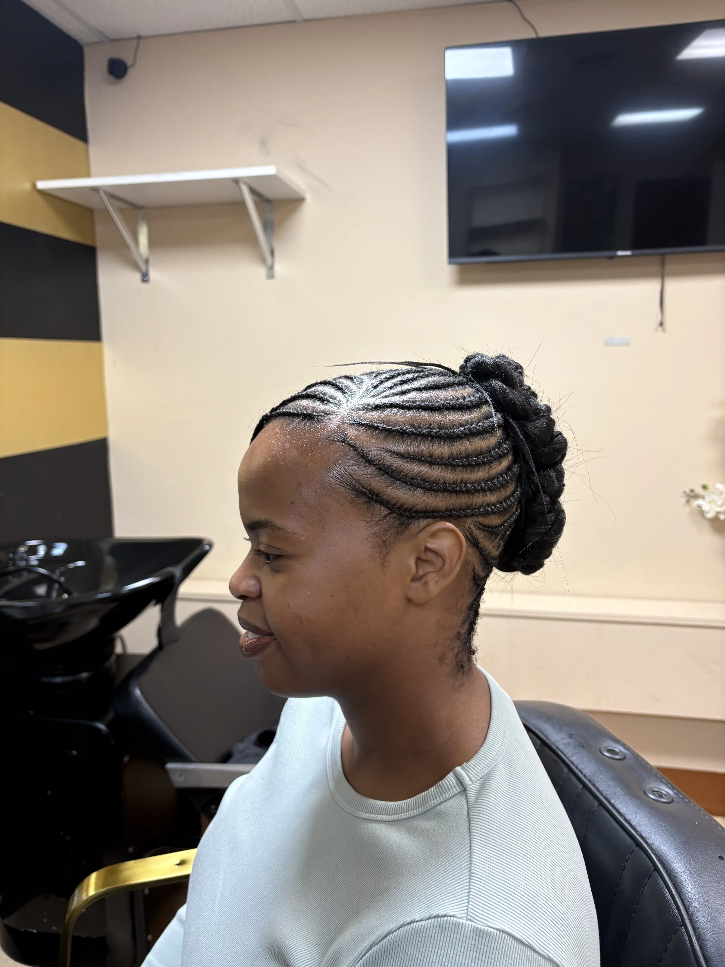 A woman with braided hair sitting in a hair salon.