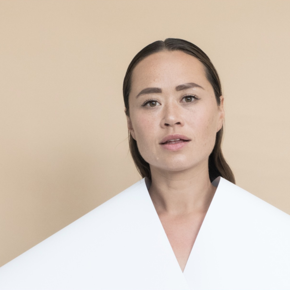 Ida Kudo synger live på scenen omgivet af varmt scenelys og musikere.