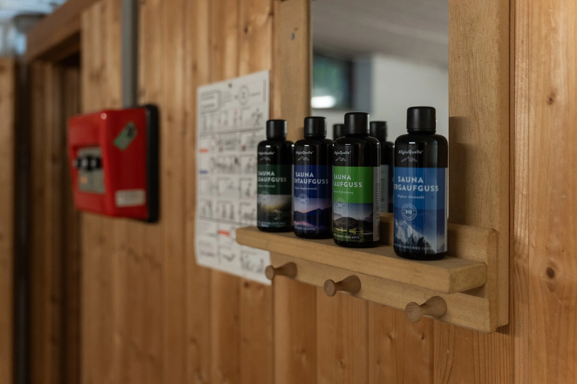 Drei Flaschen mit Sauna-Äußerung auf einem Holzregal an einer Holzwand.