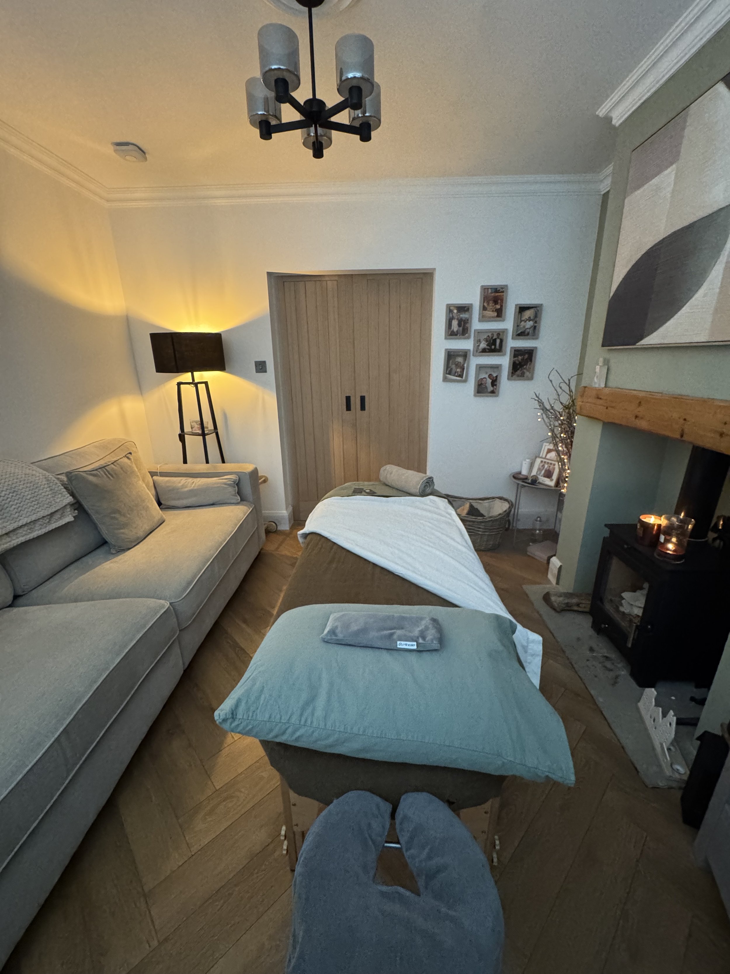 Cozy living room with sectional sofa, ottoman, fireplace, floor lamp, family photos, and modern ceiling light
