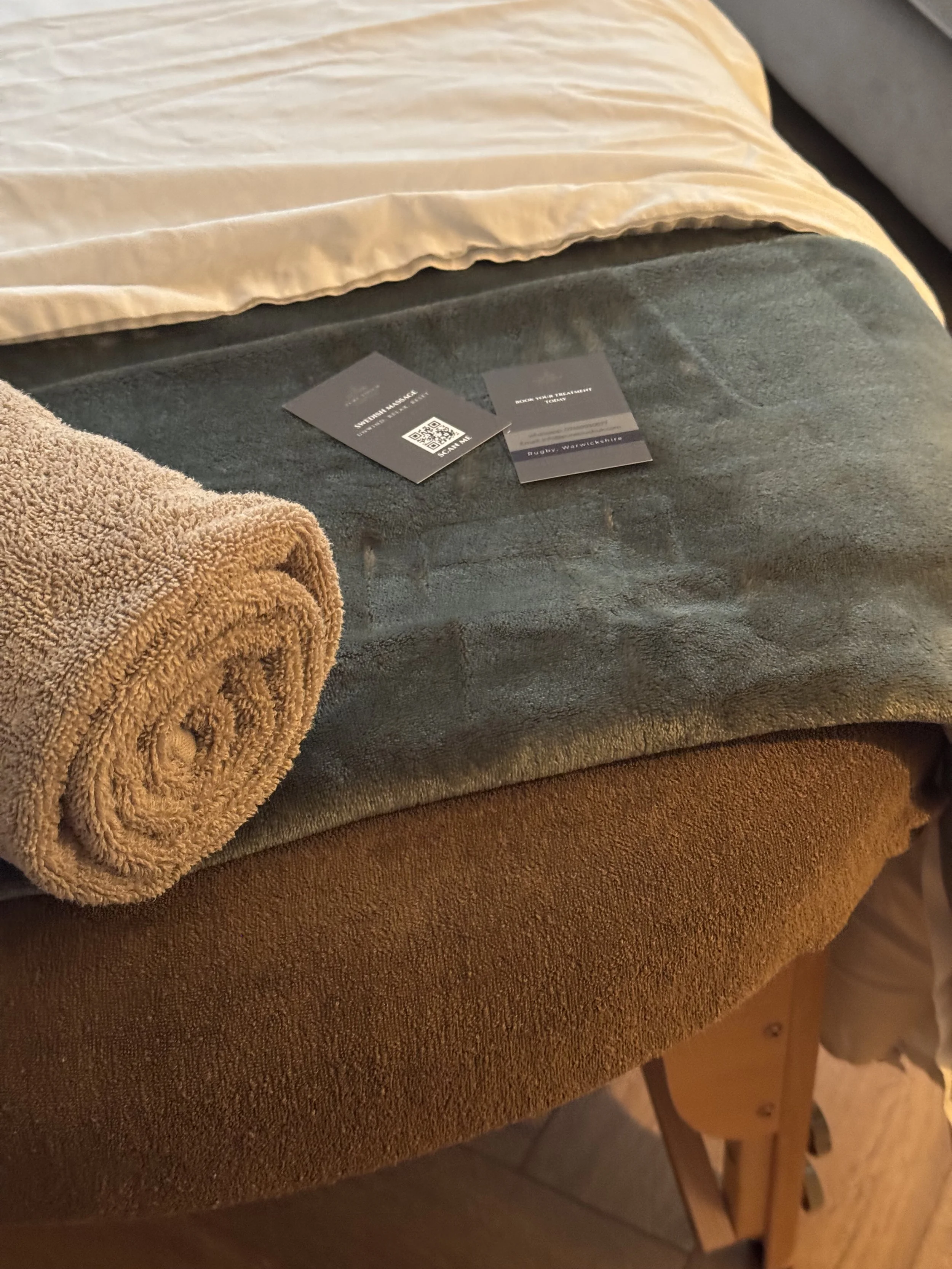 Close-up of layered beige, gray, and brown blankets with two treatment information cards on top.