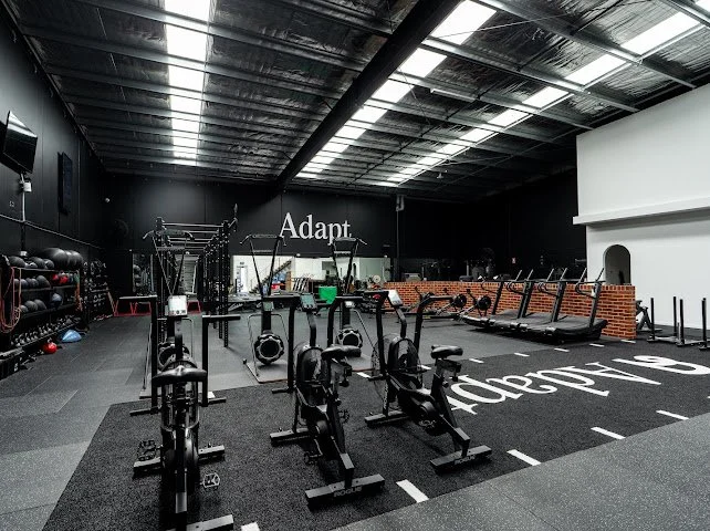 Empty indoor gym with cardio equipment, weights, and exercise areas.