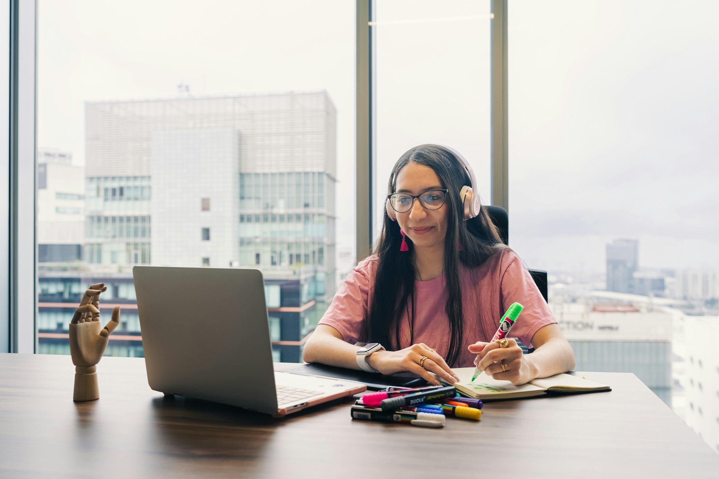 Young woman studying online at home with headphones, laptop and notes