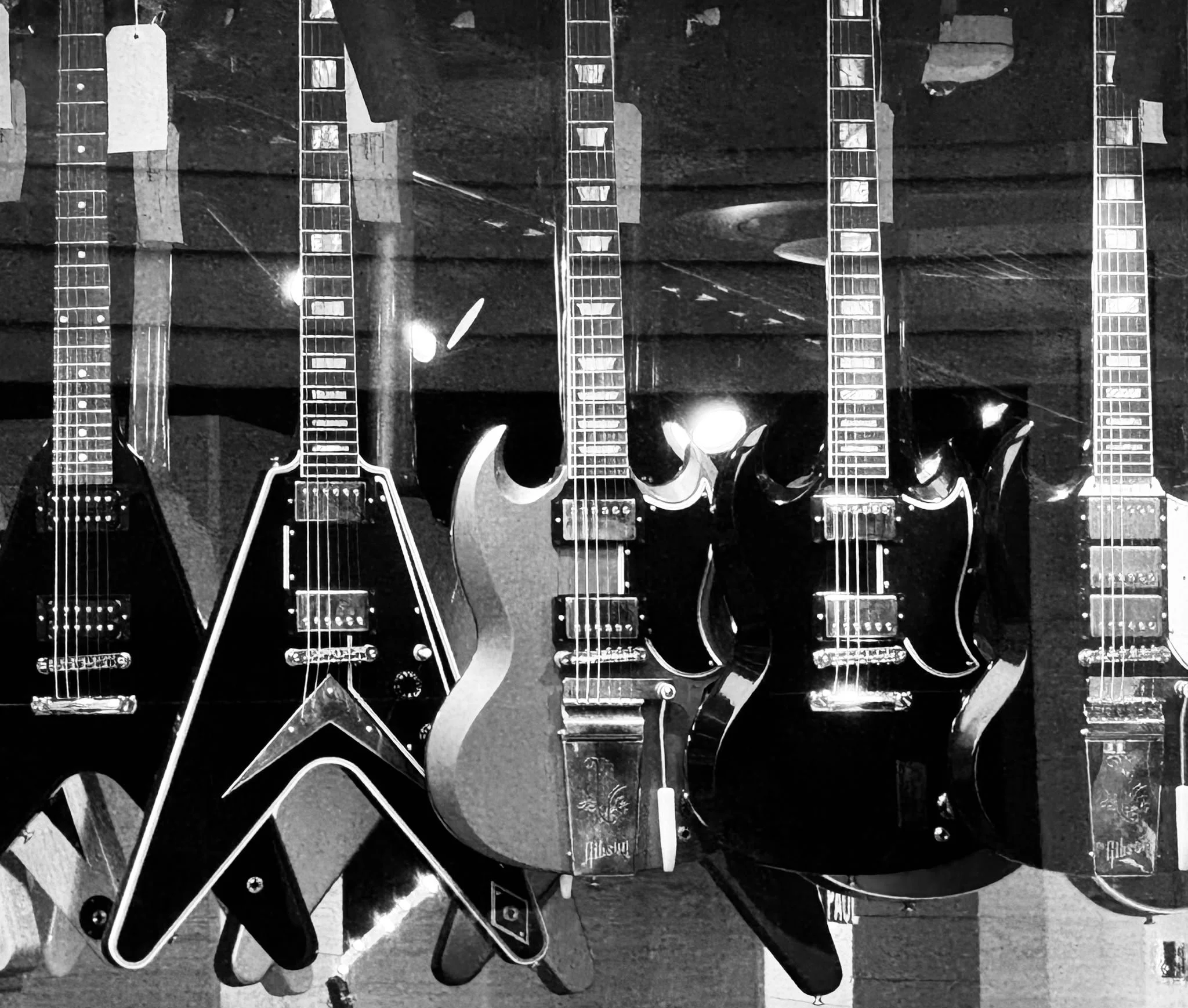 A collection of electric guitars hanging on a wall in a music store or guitar shop.