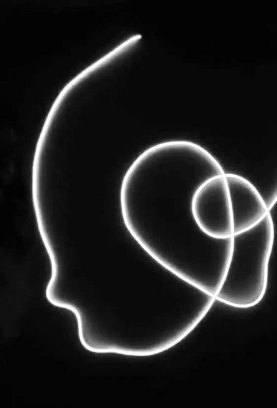 Light art of a human head silhouette with a heart shape around the brain area, created with glowing white lines on a black background.
