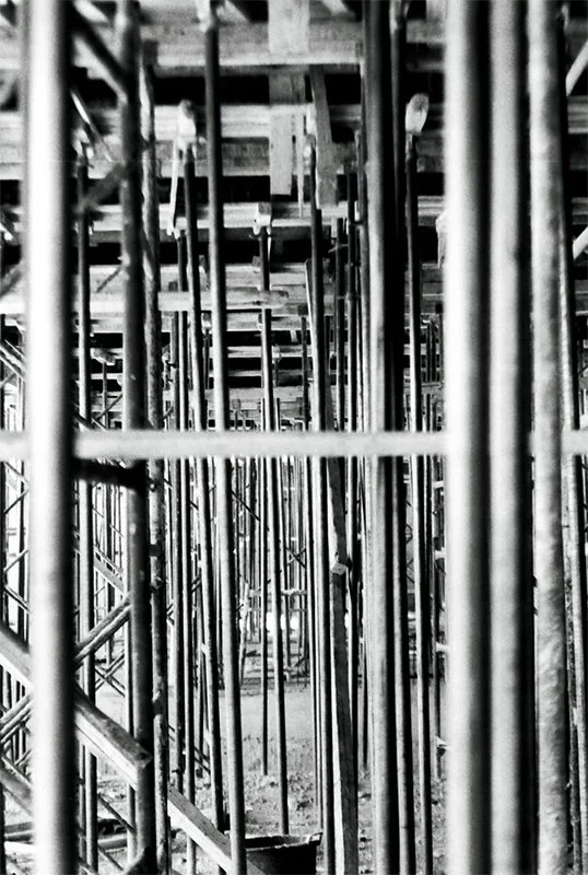 Black and white photo of metal scaffolding across multiple levels at a construction site.