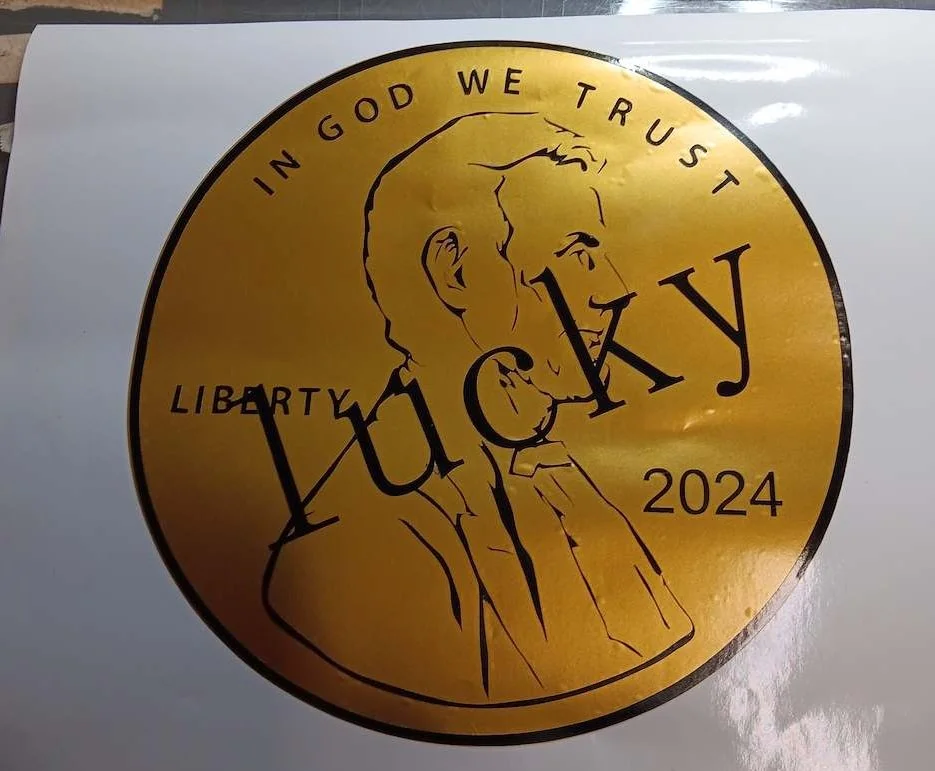 Golden decal with profile of a penny with "Lucky" imposed on it to represent a trucking company's name.