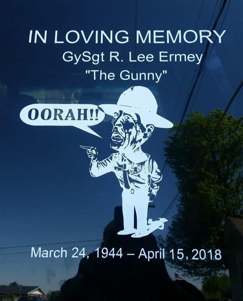 Memorial plaque for GySgt R. Lee Ermey, known as 'The Gunny,' with a cartoon image of a Marine in uniform and hat shouting 'OORAH!!' The plaque includes his birth and death dates, March 24, 1944 to April 15, 2018, and is titled 'In Loving Memory.'