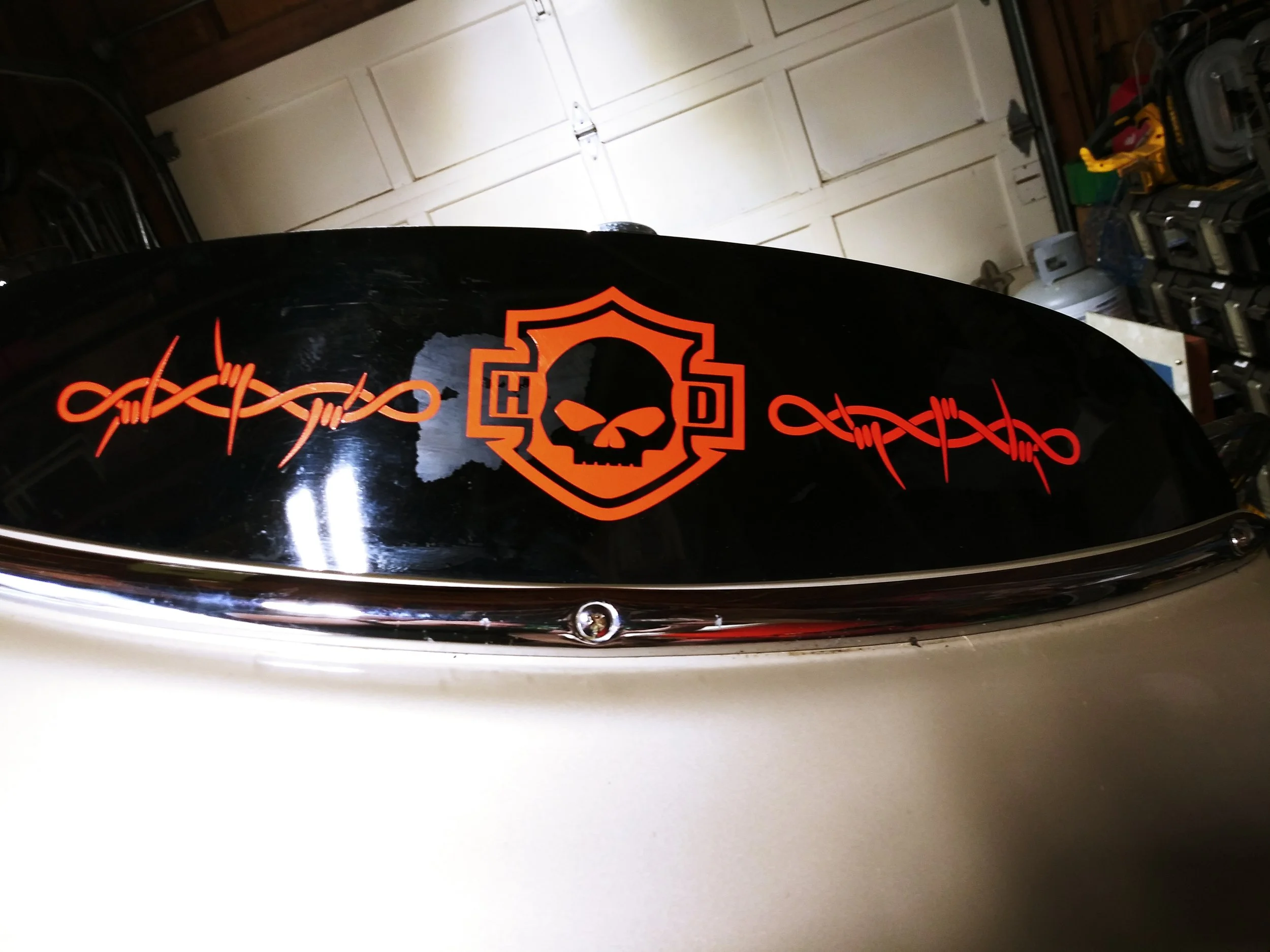 An orange HD skull logo and barbed wire design on the windshield of a motorcycle