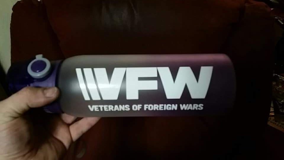 A person holding a water bottle with the logo of Veterans of Foreign Wars (VFW) on it.
