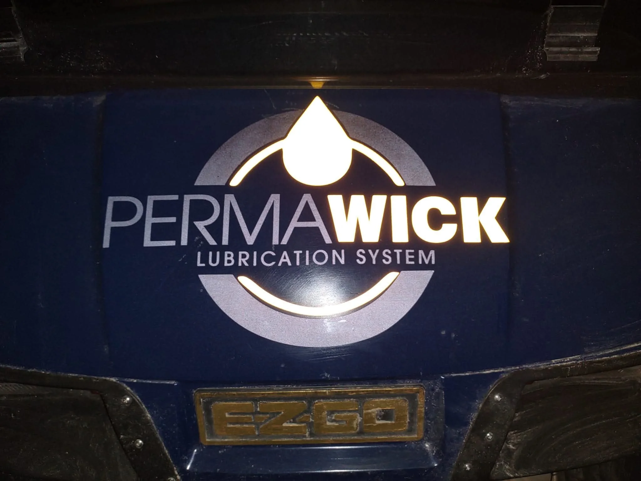 A golf cart decal that reads 'PERMAWICK Lubrication System' with a logo in reflective vinyl material