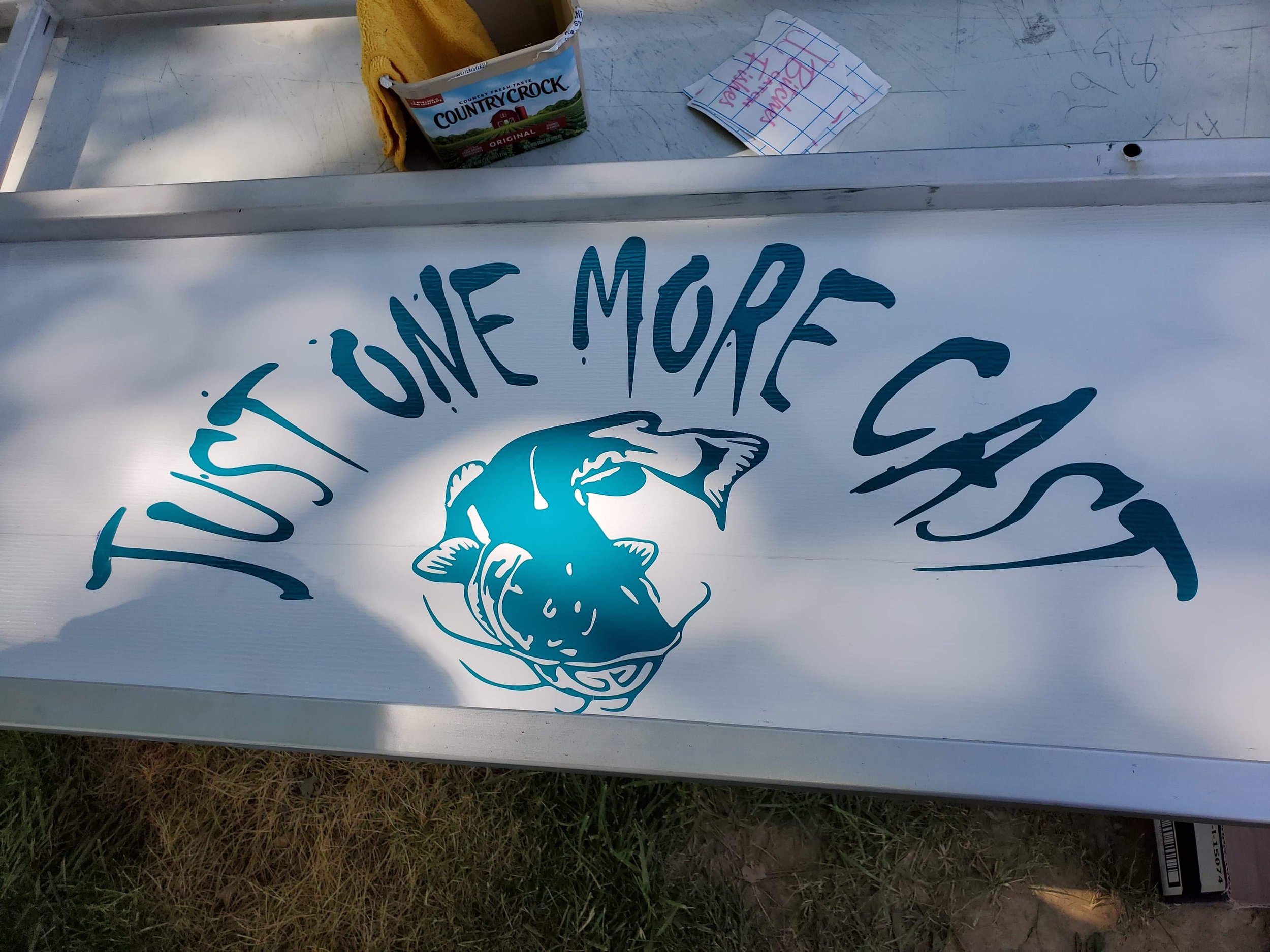 A customer's decal he had made for the back of his boat that reads "one more cast" and a large catfish in sparkling green vinyl.