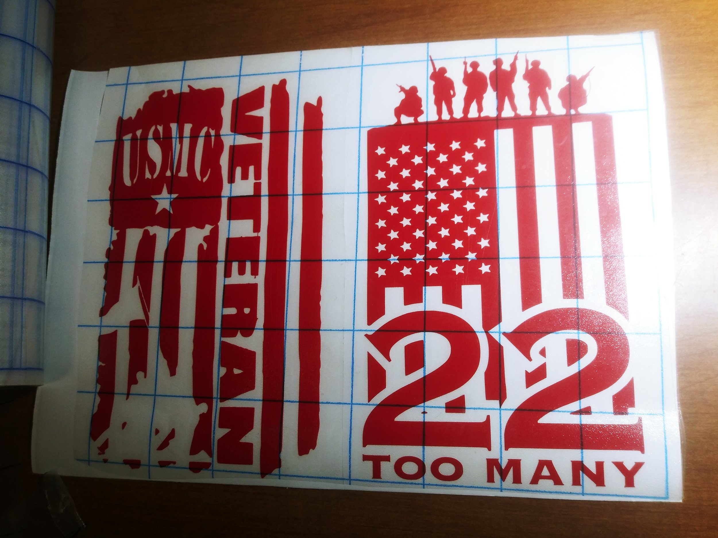 Red stencil-style American flag with soldiers on top, and the words 'TOO MANY' in reference to veteran suicides and a decal with "USMC veteran" incorporated  with the American flag.