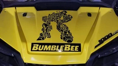 The front of a yellow side by side with a Bumblebee logo featuring a robotic bee in black, and the word 'Bumblebee' in bold black letters.