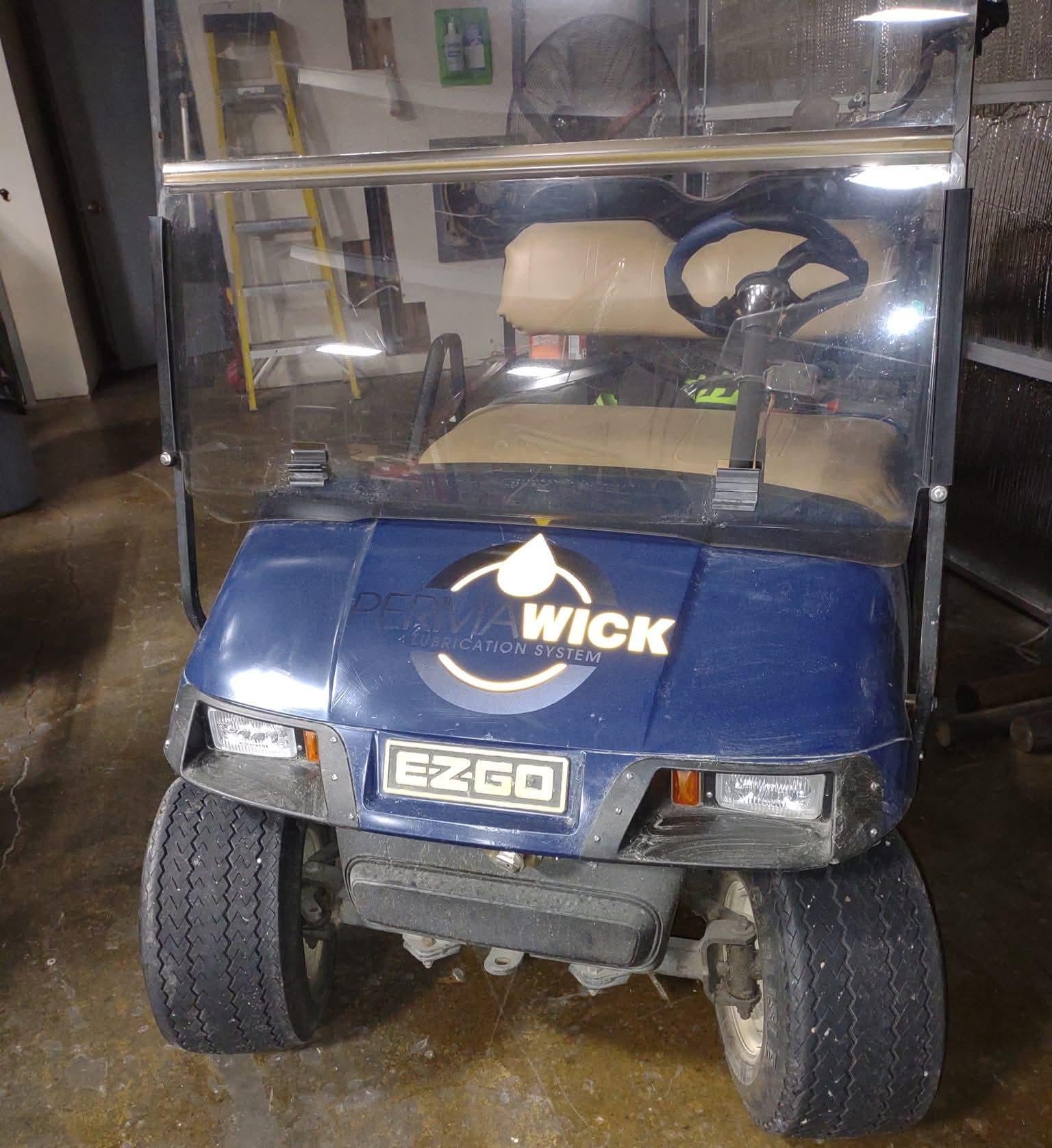 A blue golf cart with a decal that reads 'PERMAWICK' and a the company logo.