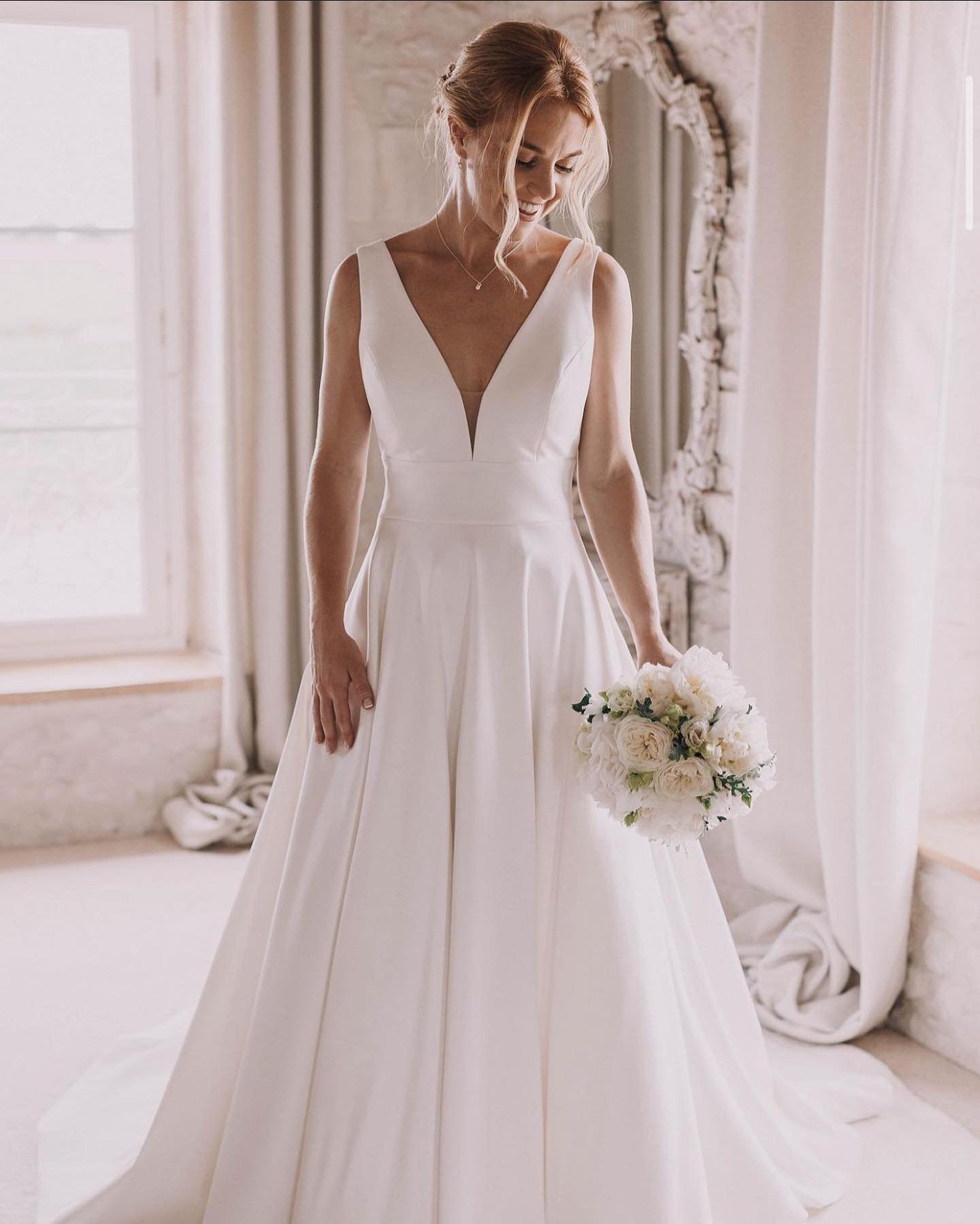 A bride in a white wedding dress holding a bouquet of white roses.