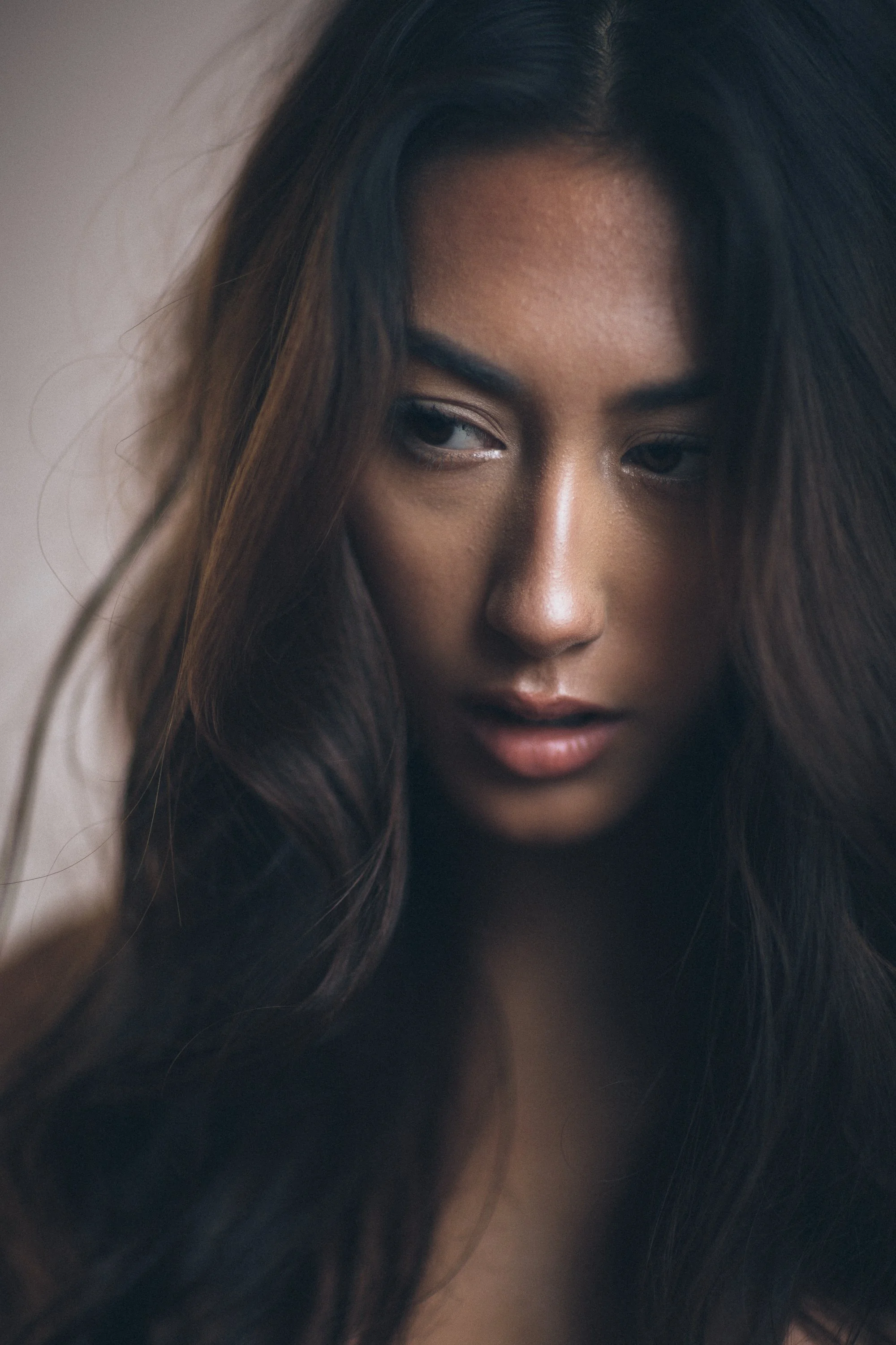 Close-up of a woman's face with layered dark hair, showing only part of her face, focusing on her left eye and cheek.