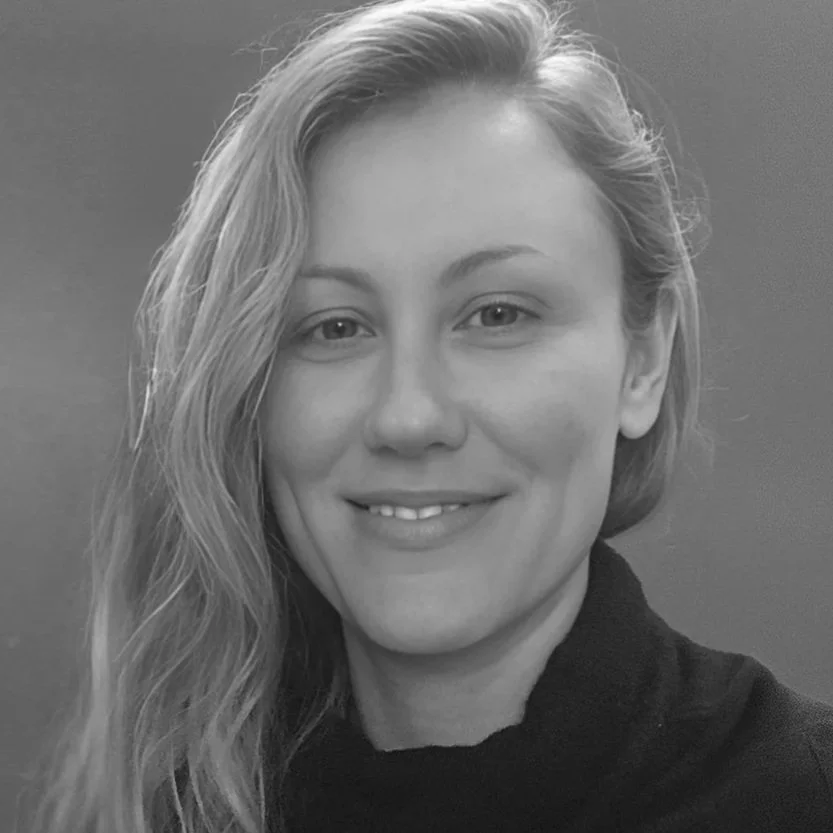 Black and white portrait of a smiling woman with long hair, wearing a dark top.