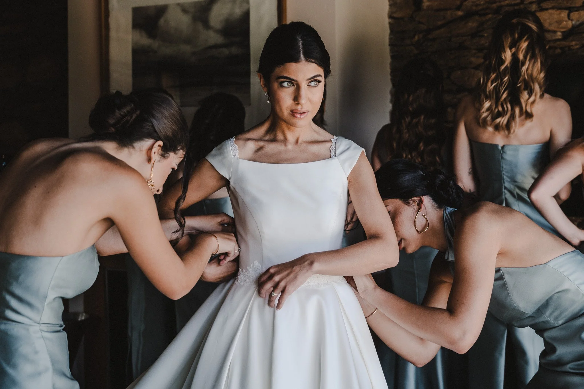Des femmes en robes de mariage sont aidées à ajuster la robe d'une mariée lors d'un mariage