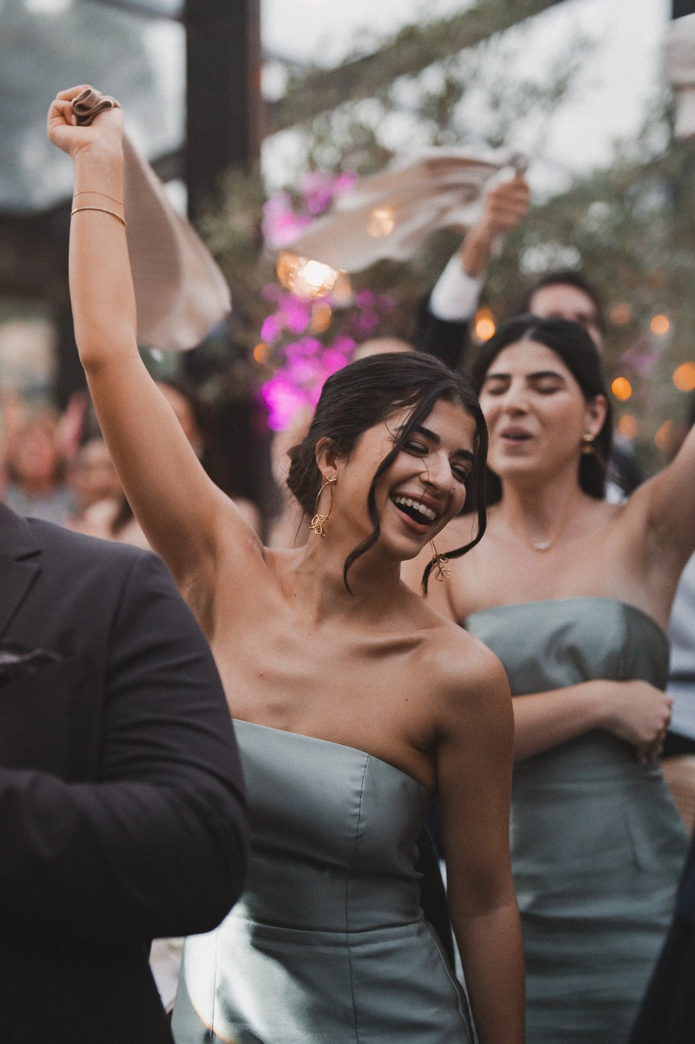 Groupe de personnes lors d'une fête ou d'un mariage, souriantes et portant des robes de soirée, avec des décorations florales en arrière-plan.