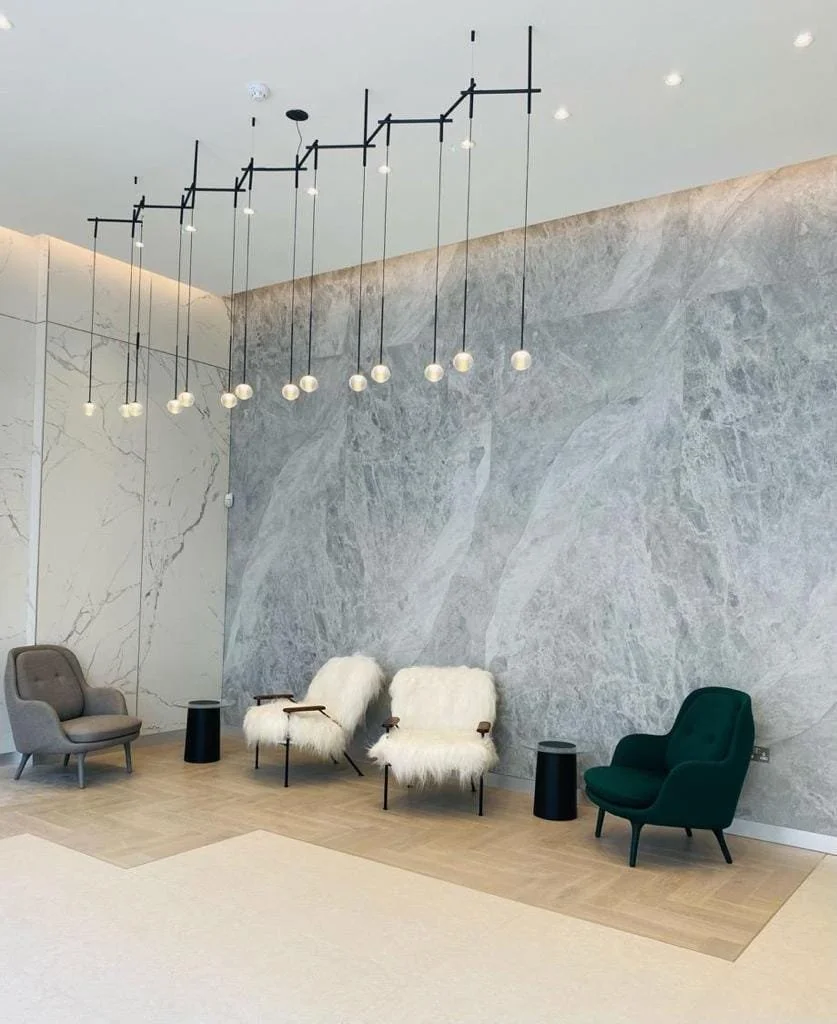 Modern living room with marble walls, sculptural pendant lights, and four mid-century lounge chairs