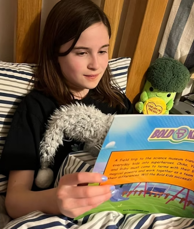 Young girl reading the bold kids the origin book smiling