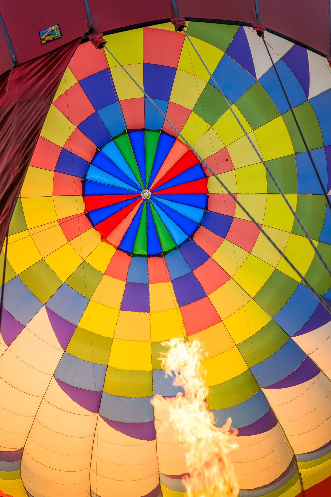 The interior of a colorful hot air balloon with a rainbow pattern, and a flame inflating it.