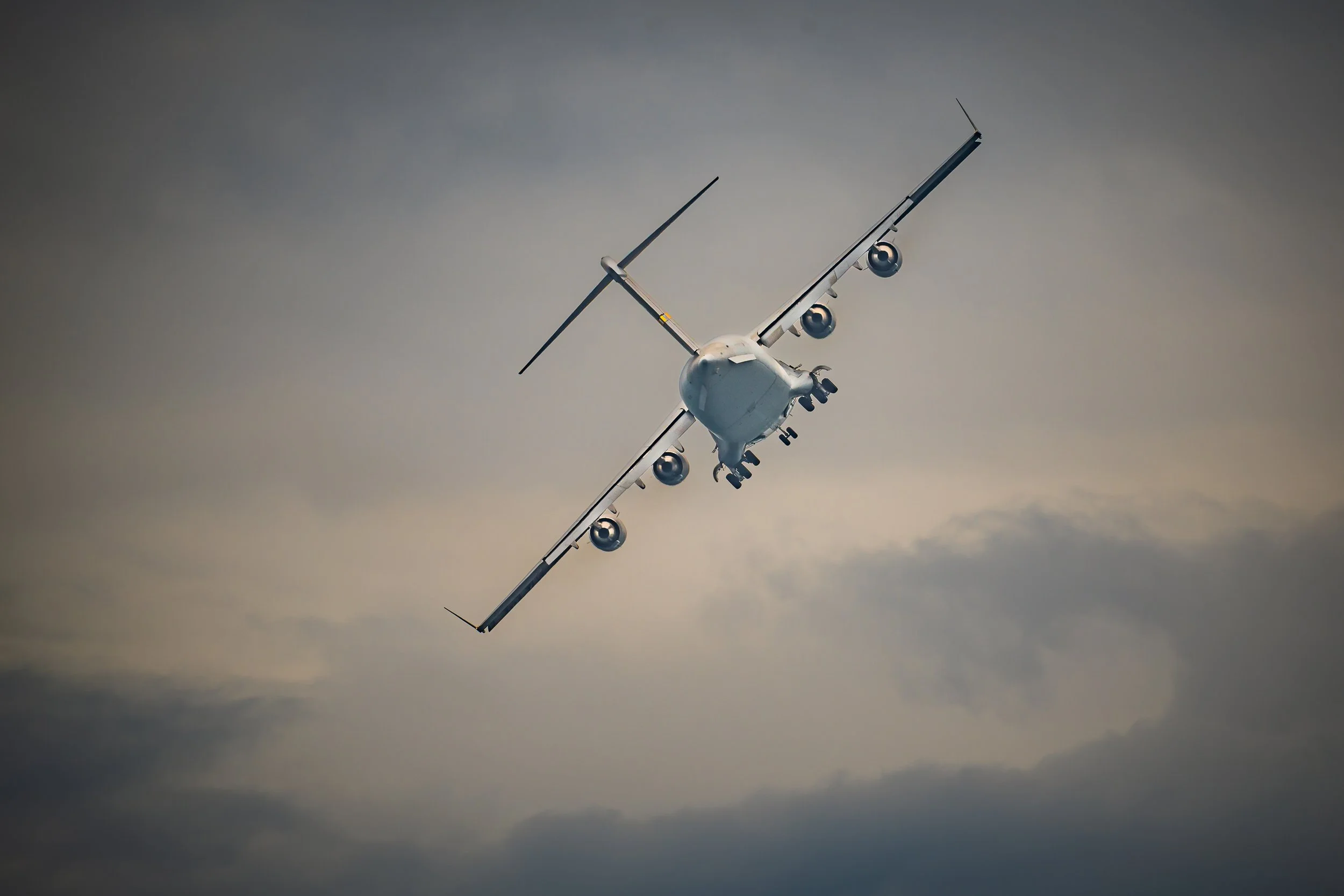 An airplane flying at a steep angle against a cloudy sky.