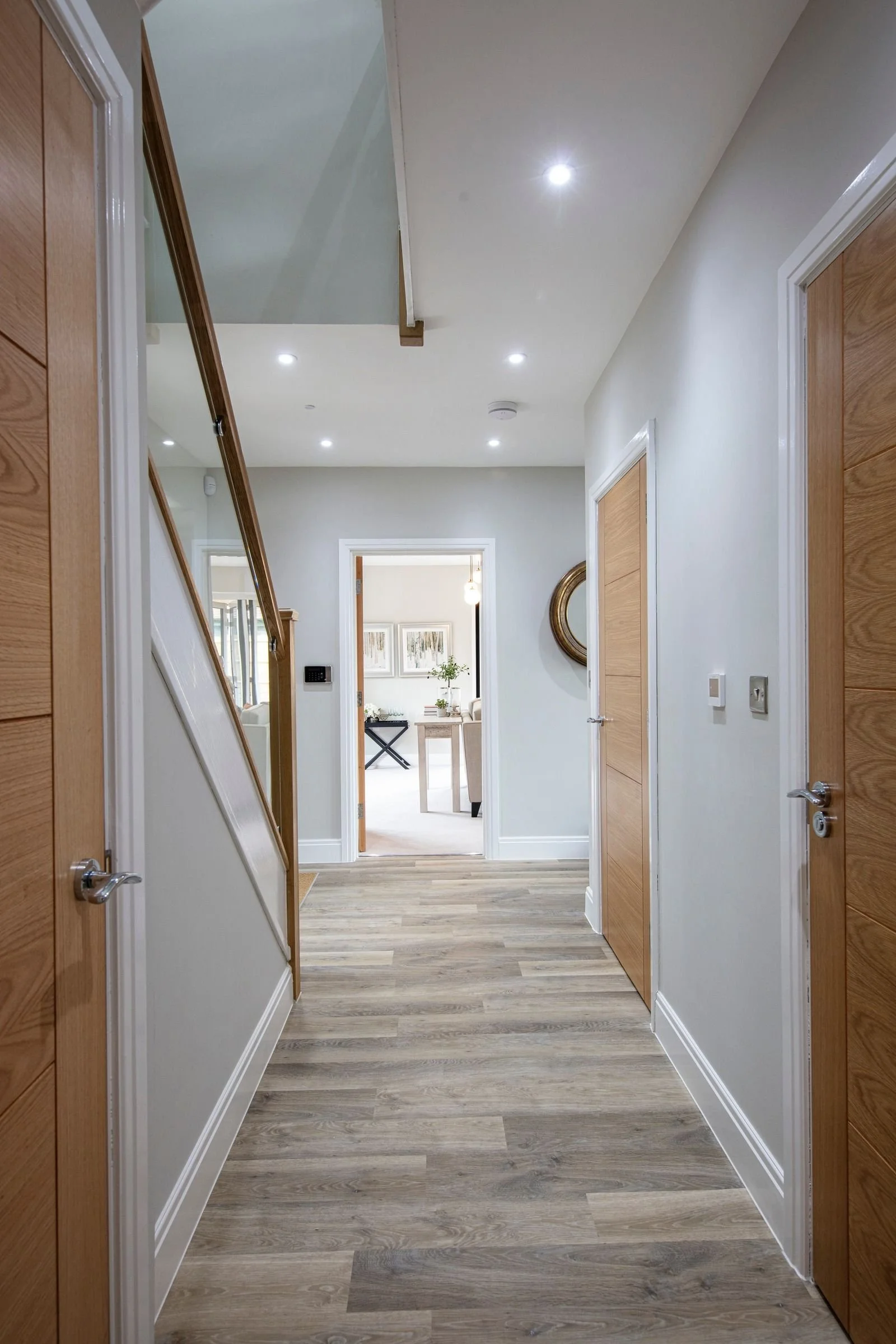 Ground-floor hallway with oak internal doors and wood-effect flooring.